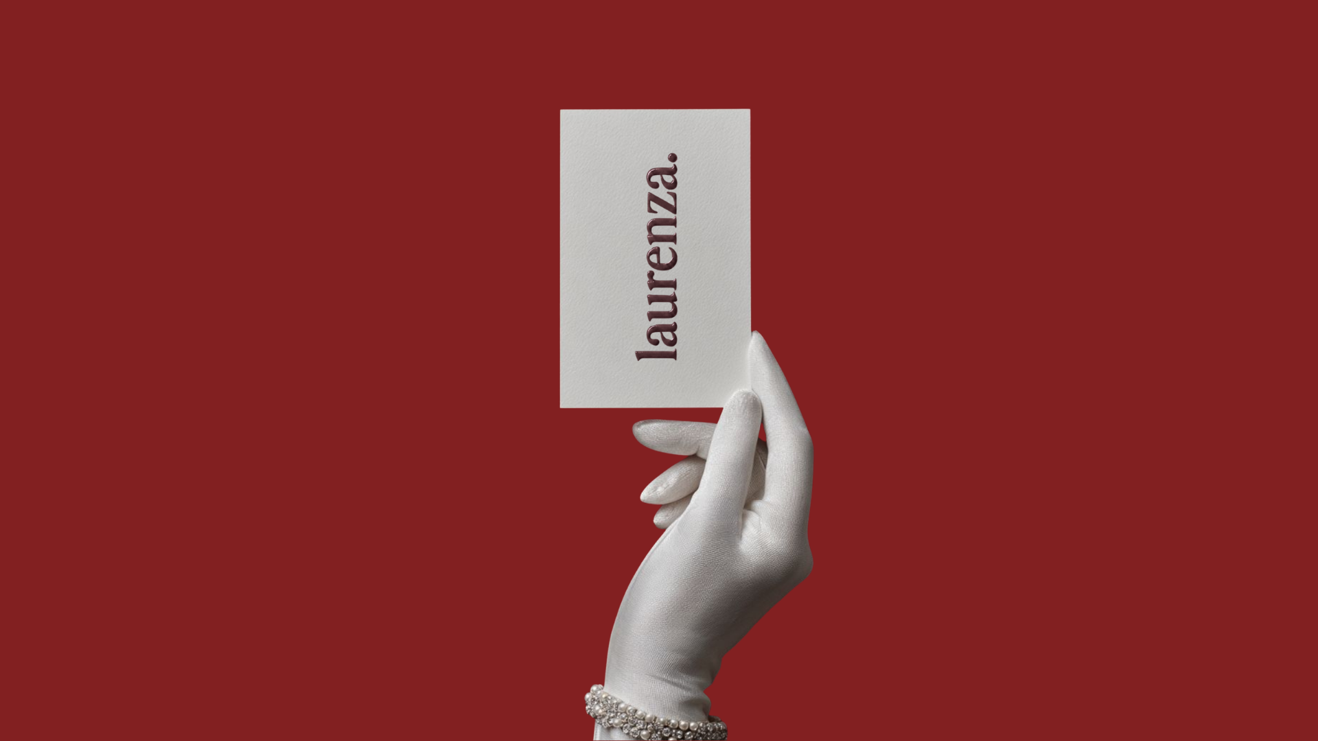 A hand wearing a white glove holds a white card with the word "lauenza" written vertically in dark letters against a solid red background.