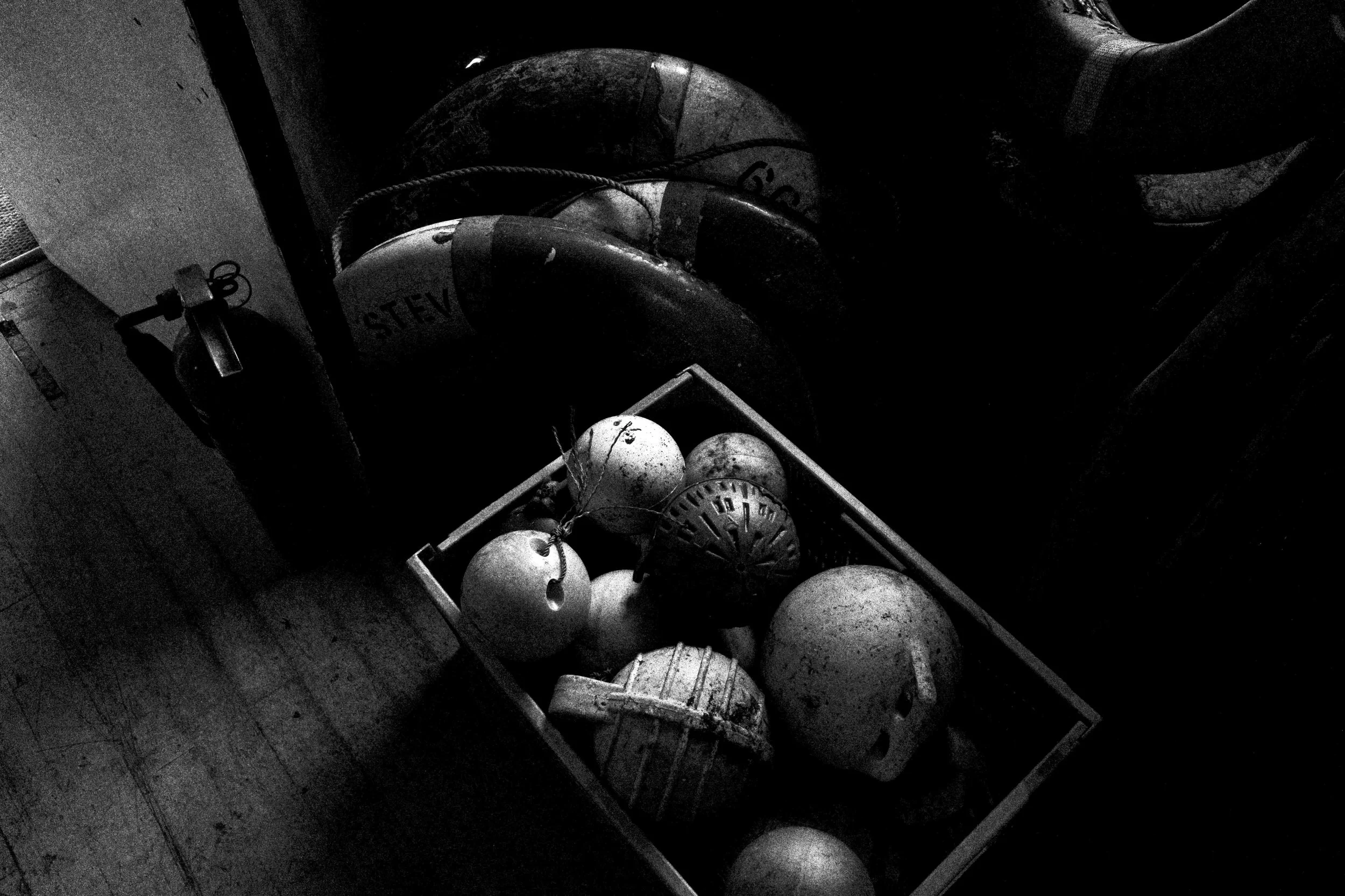 Black and white photo of a basket filled with several vintage baseball gloves and a baseball in the foreground.
