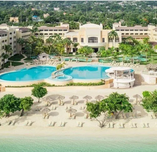 Aerial view of Iberostar Waves Rose Hall Beach in Montego Bay, Jamaica, showing the beachfront resort, swimming pools and Caribbean Sea.