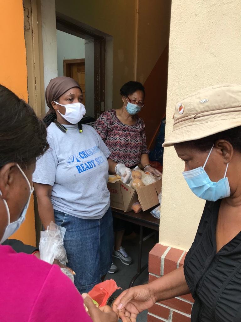 Women wearing masks distributing food or supplies during a community event