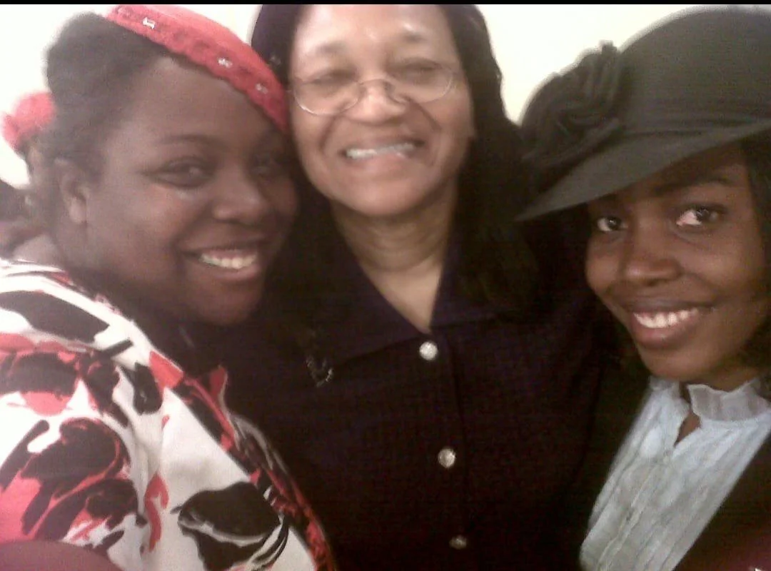 Three women smiling and posing closely together for a photo.