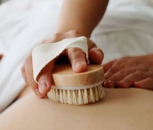 Person receiving a back massage with a brush.