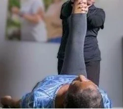 A person lying on an examination table with their eyes closed, while a medical professional stands nearby holding a clipboard.