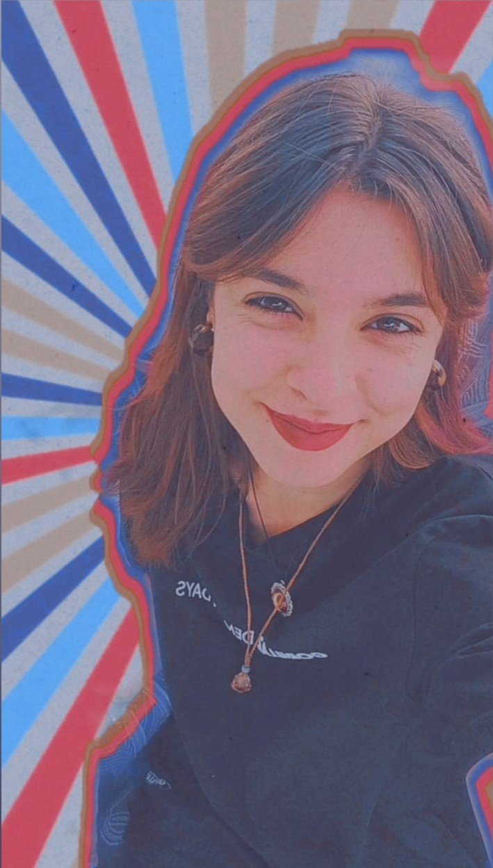 Mulher sorrindo, com cabelo castanho, usando roupas pretas e acessórios, fundo com padrão de raios coloridos em vermelho, azul e bege