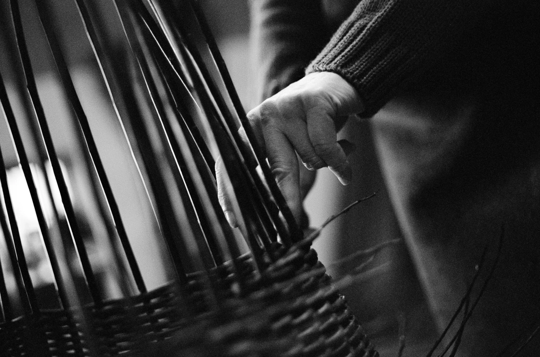 Close-up of a person's hand pressing keys on a piano keyboard, black and white photo.