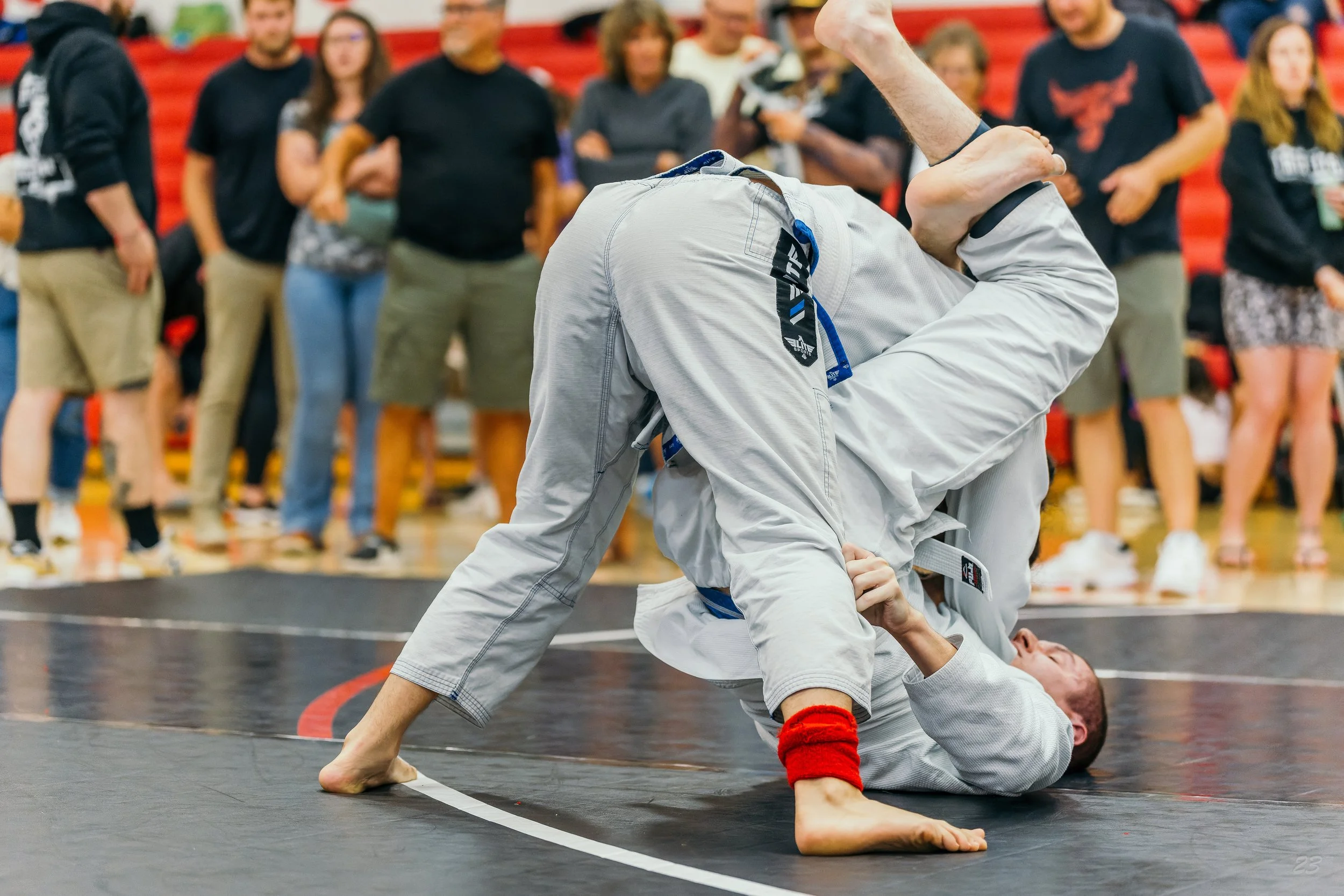 Two Brazilian jiu-jitsu competitors in white gis grapple during a match at the South Dakota Open.
