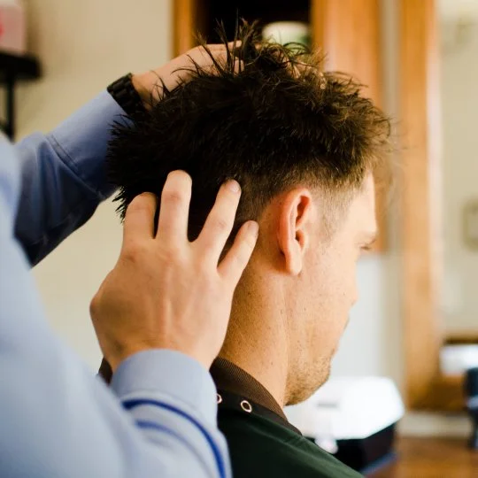 Barber styling a man's hair from the back view