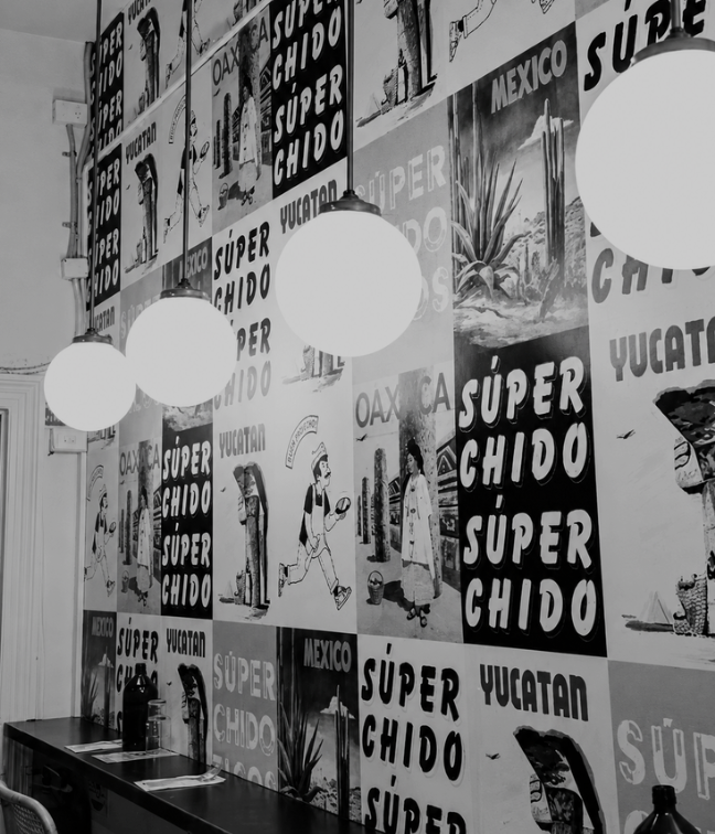 Interior wall decorated with posters and artwork featuring Mexican themes, including