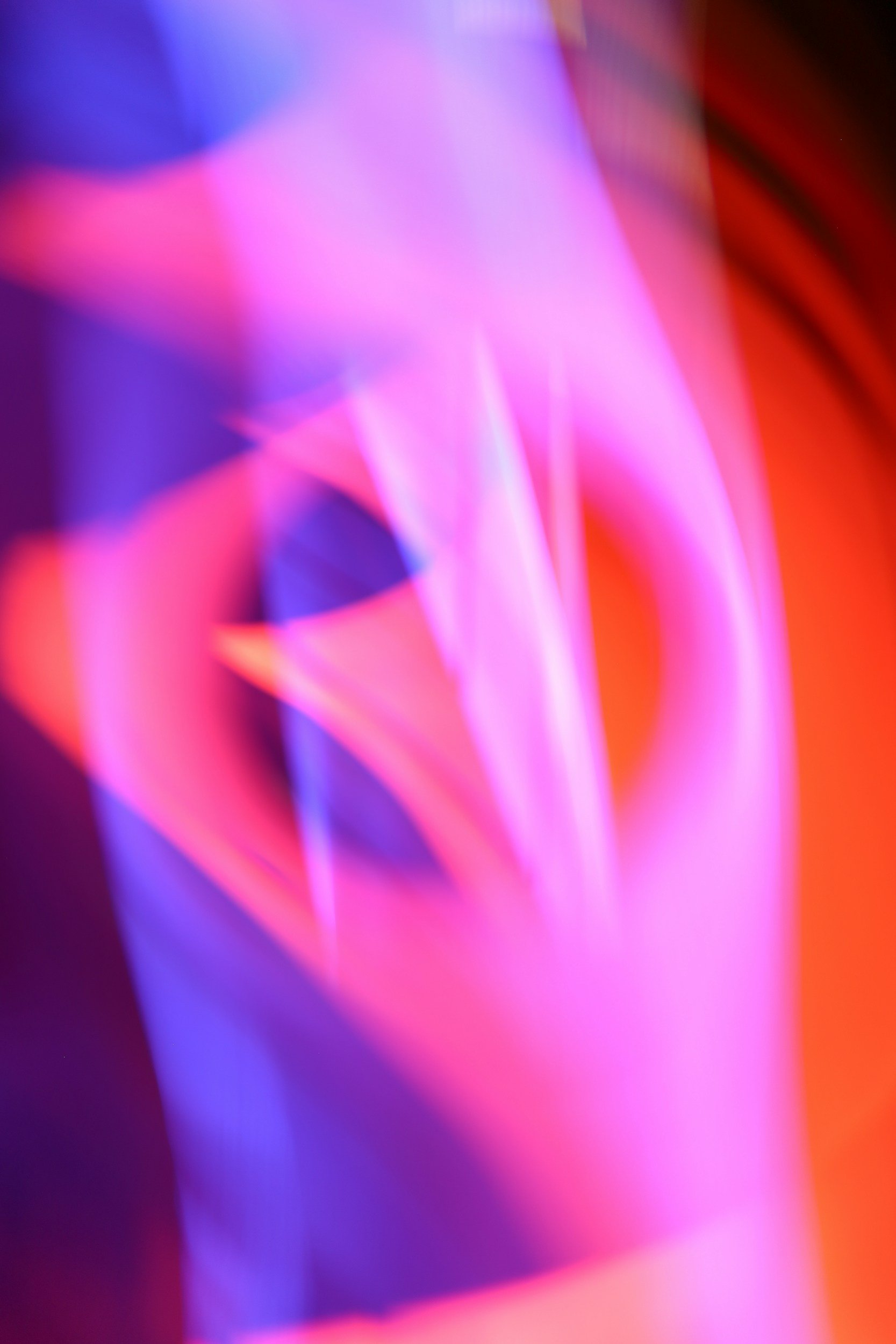 Abstract background with vibrant neon colors in pink, purple, and red hues, featuring blurred, flowing shapes.