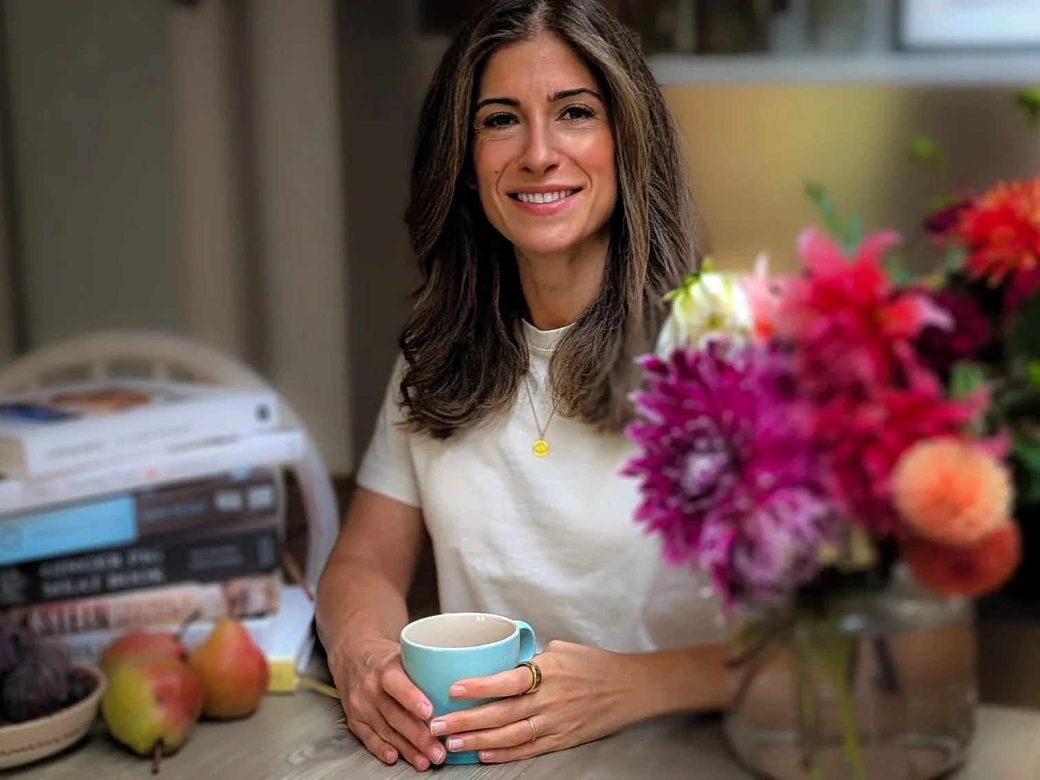 Woman smiling with a bouquet of flowers and fresh pears and figs