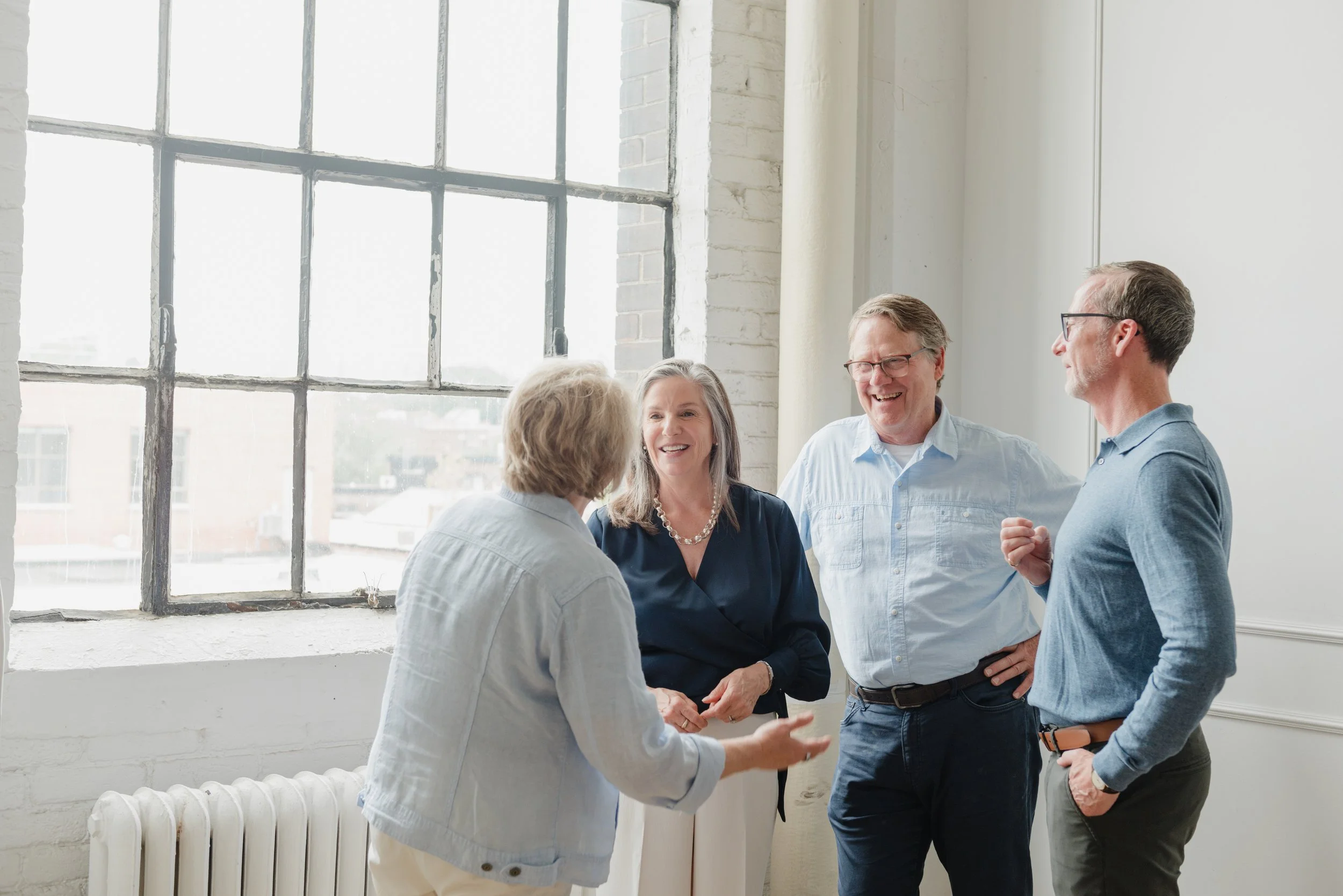 A group of four middle-aged adults, two men and two women, including Wendy Shami engaged in conversation.