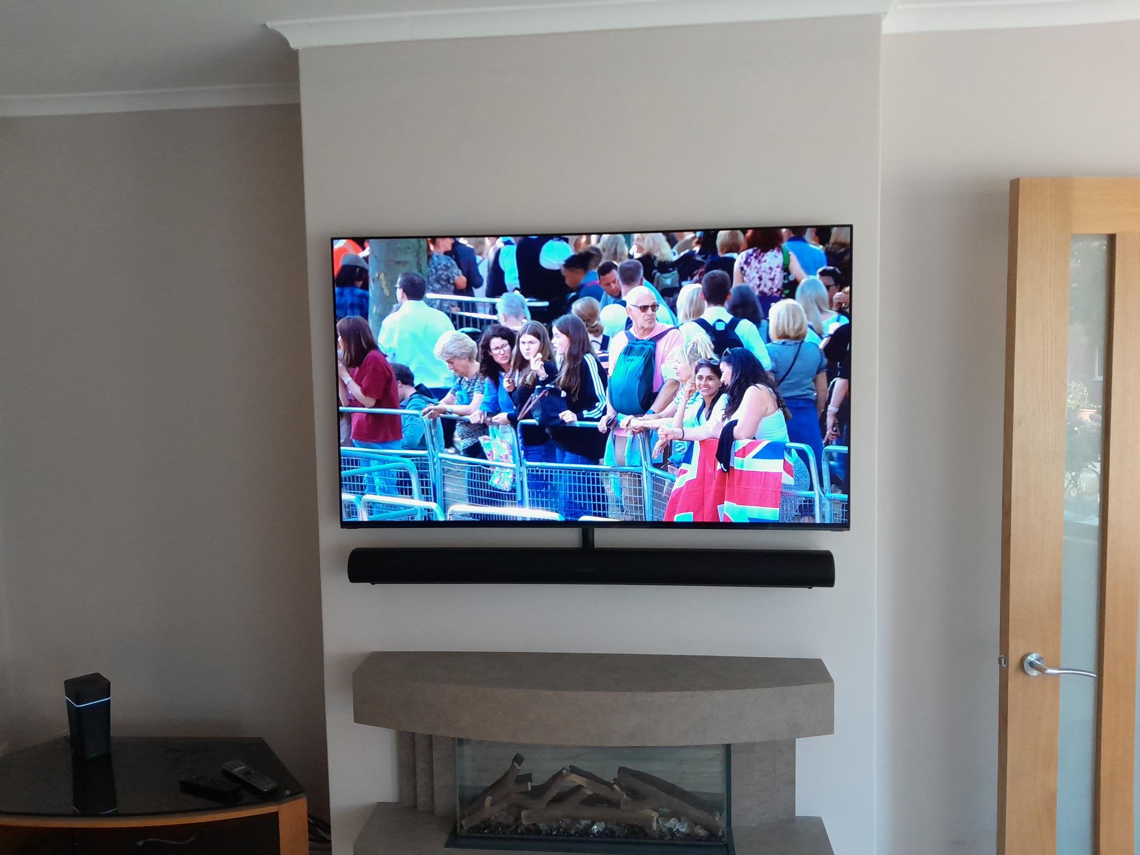 A wall mounted television and soundbar installed above a fireplace with concealed cabling.