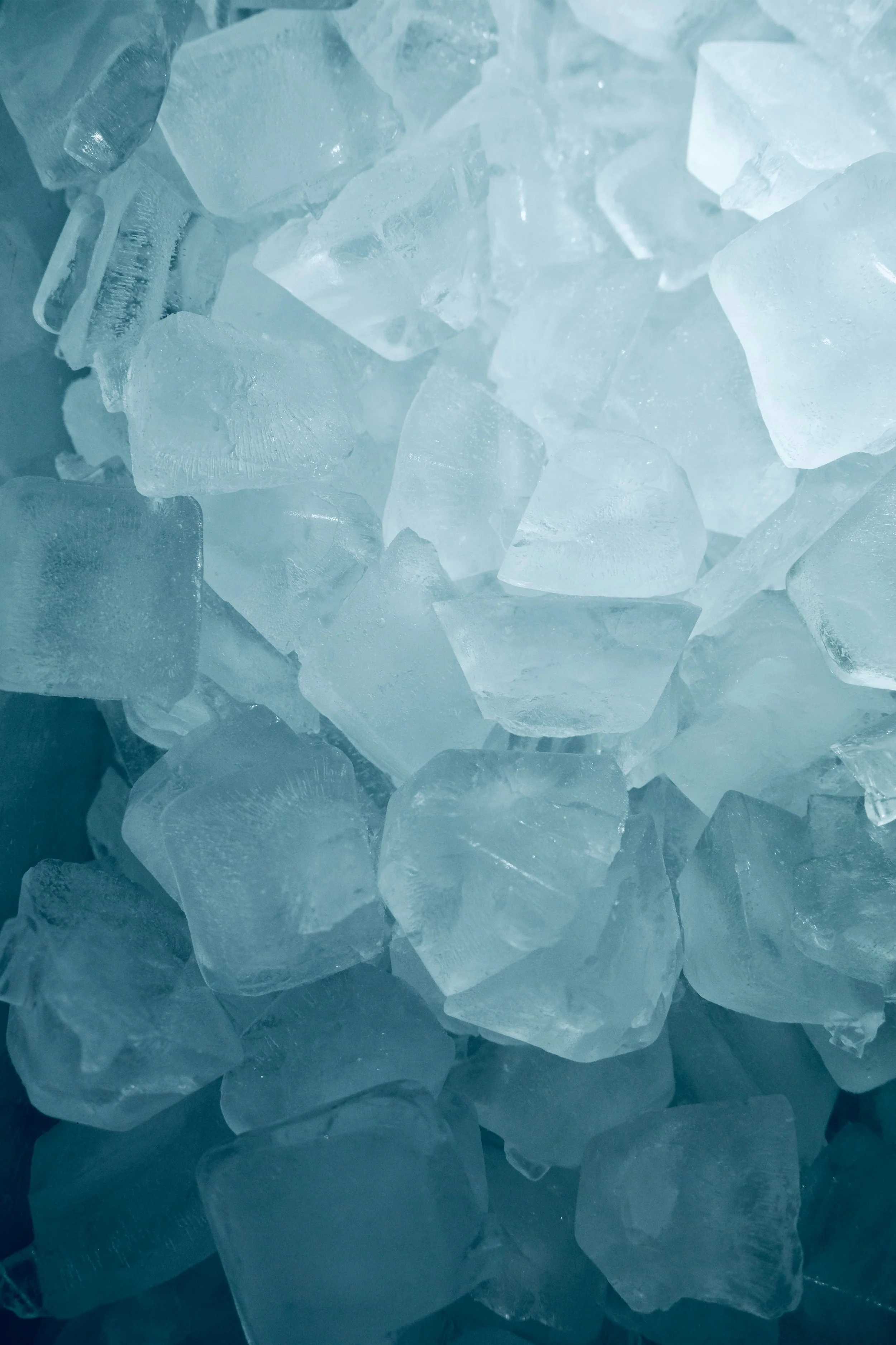 Close-up of irregularly shaped, semi-transparent ice cubes with a slightly bluish hue.