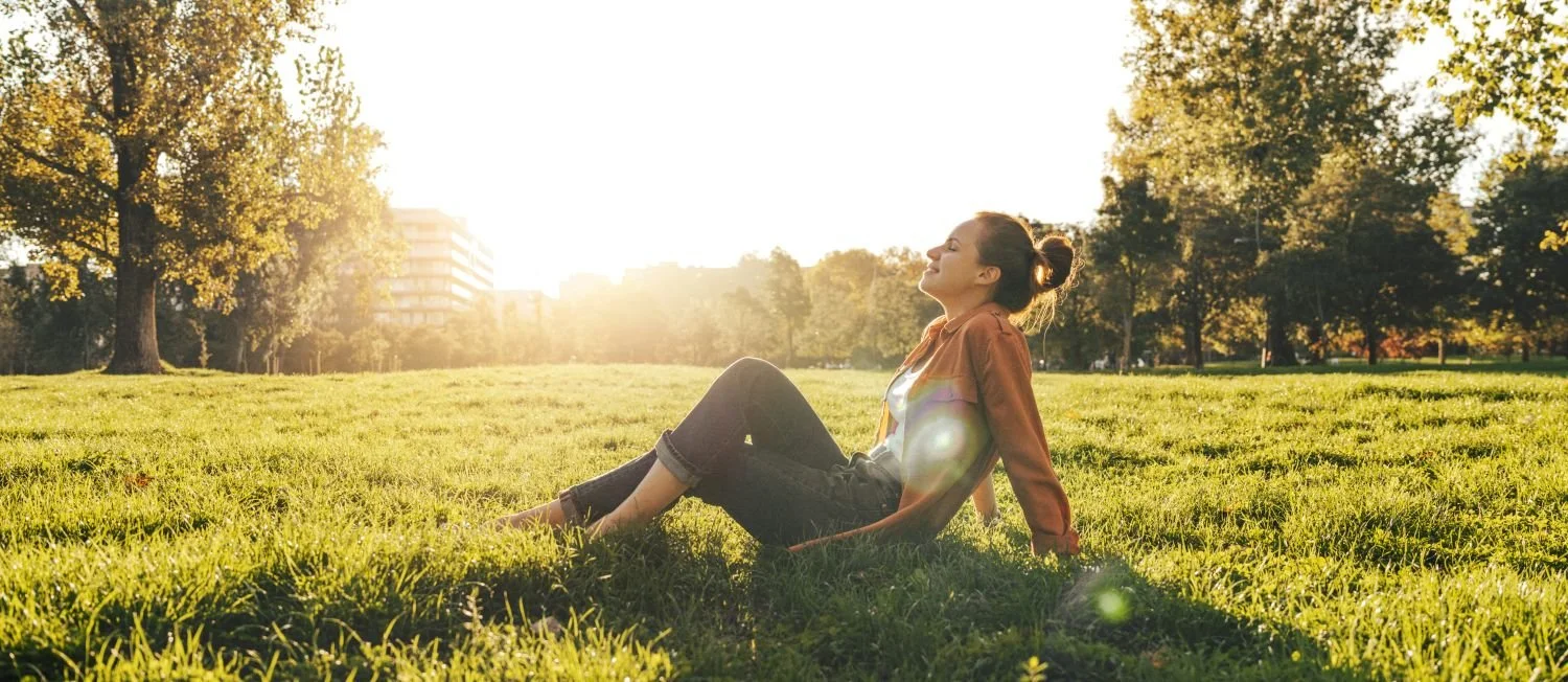 Peaceful woman relaxing outdoors in a sunny park, representing wellness and peace of mind with Reclaim Direct Primary Care in Burleson, TX.