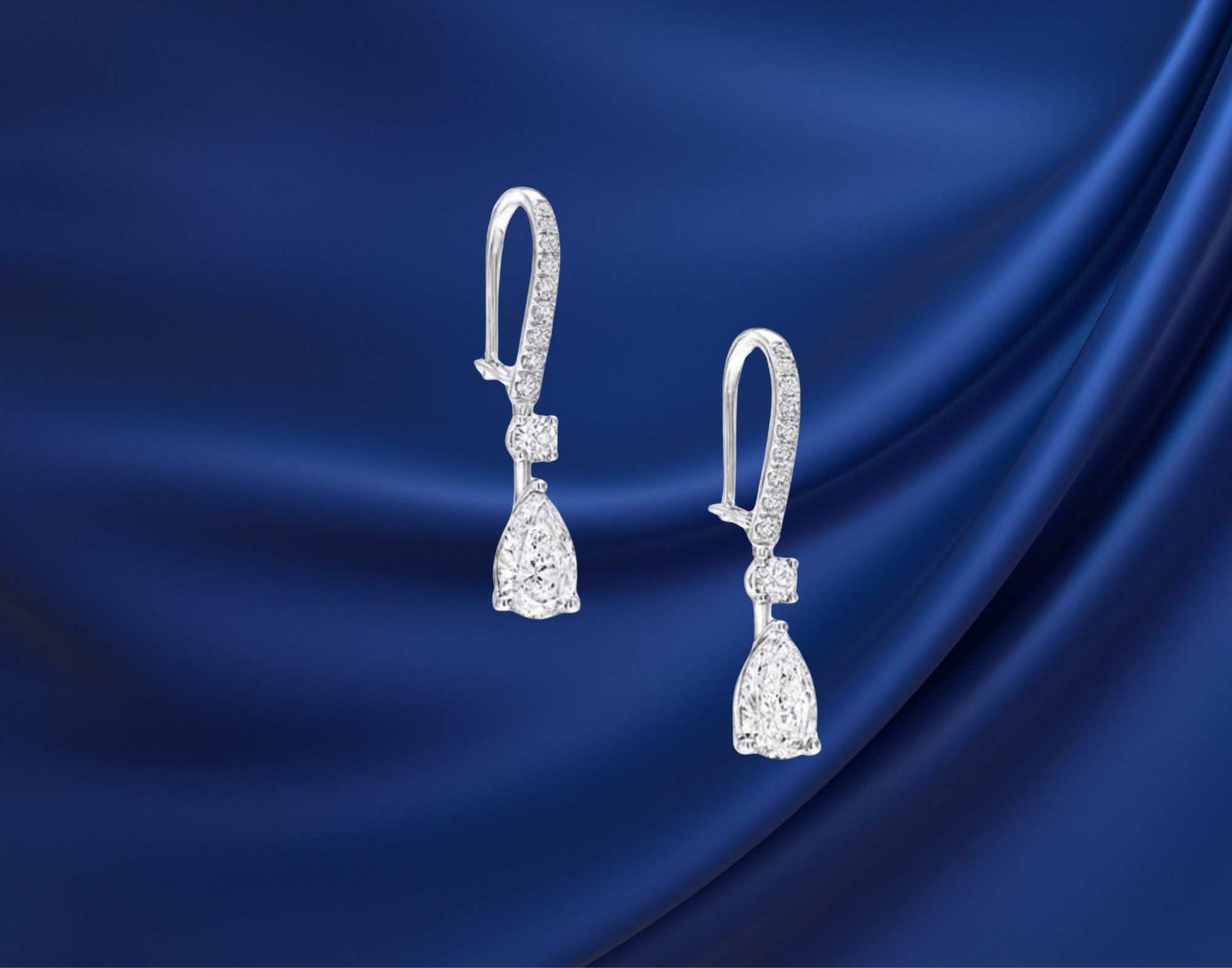 Diamond drop earrings displayed on blue satin background highlighting Direct Manufacturer Pricing at SINO Fine Jewelry in South Florida.