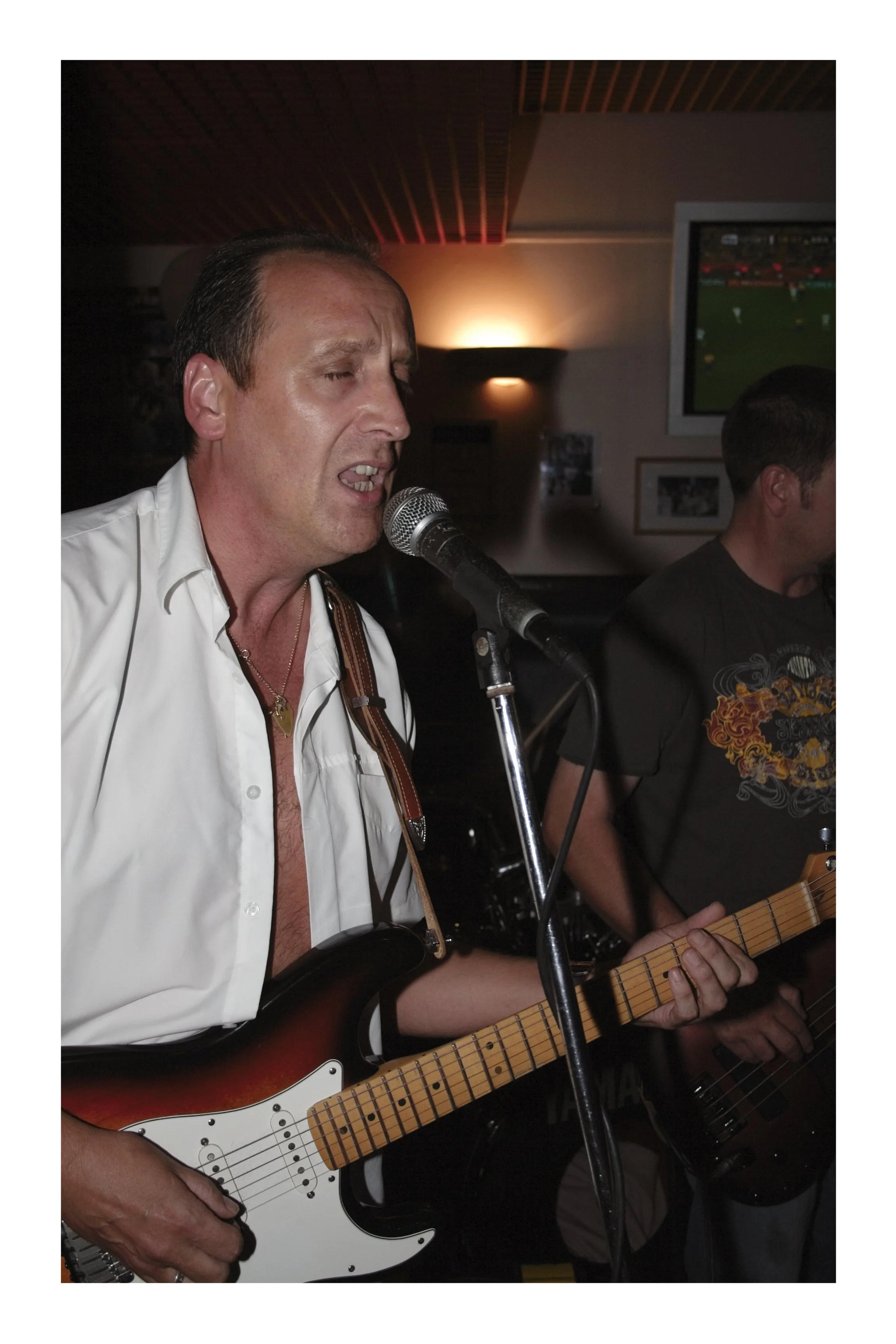 A close up of a man singing and playing guitar