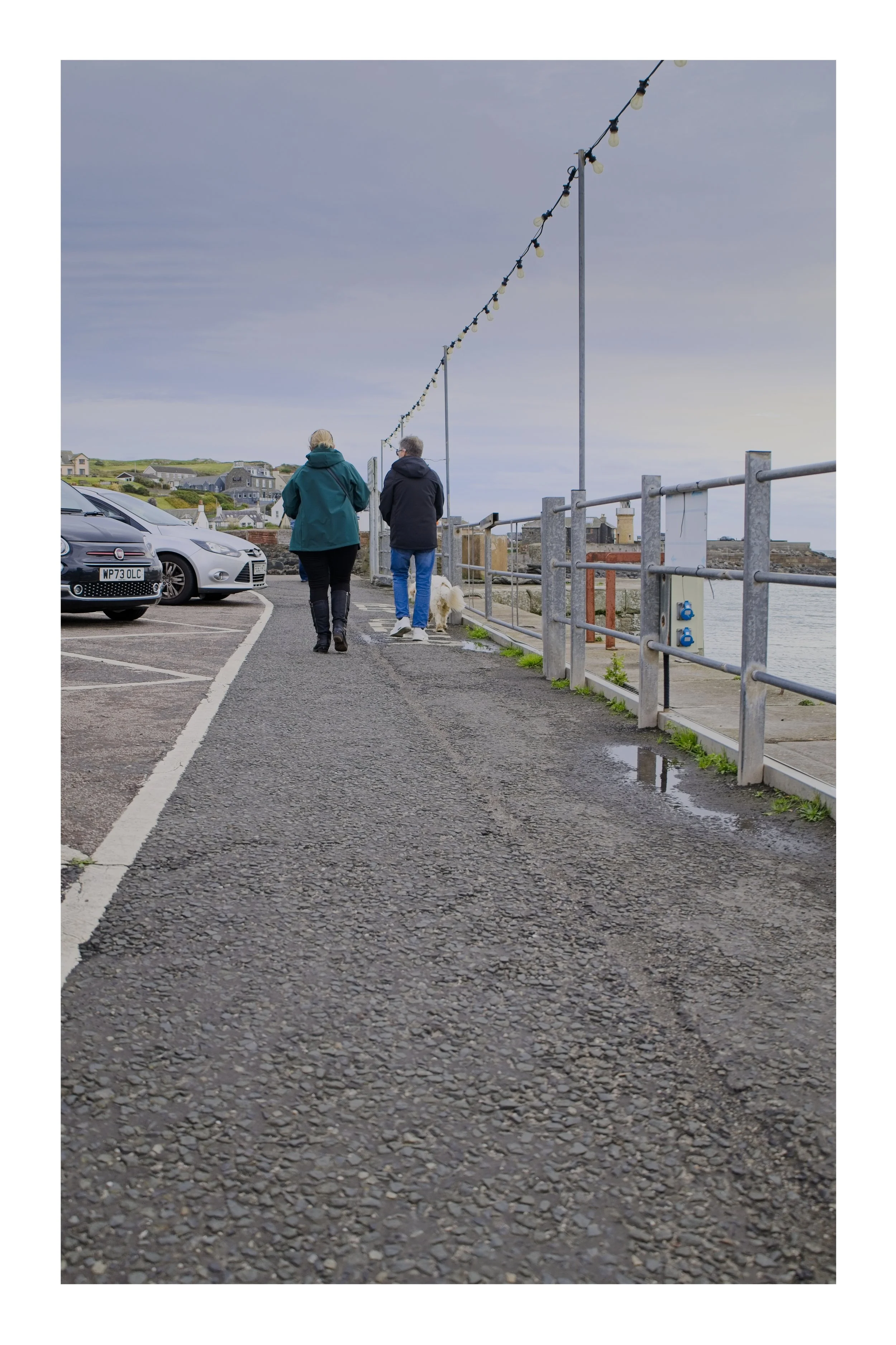 Two people walking along the harbour road in Portpatrick