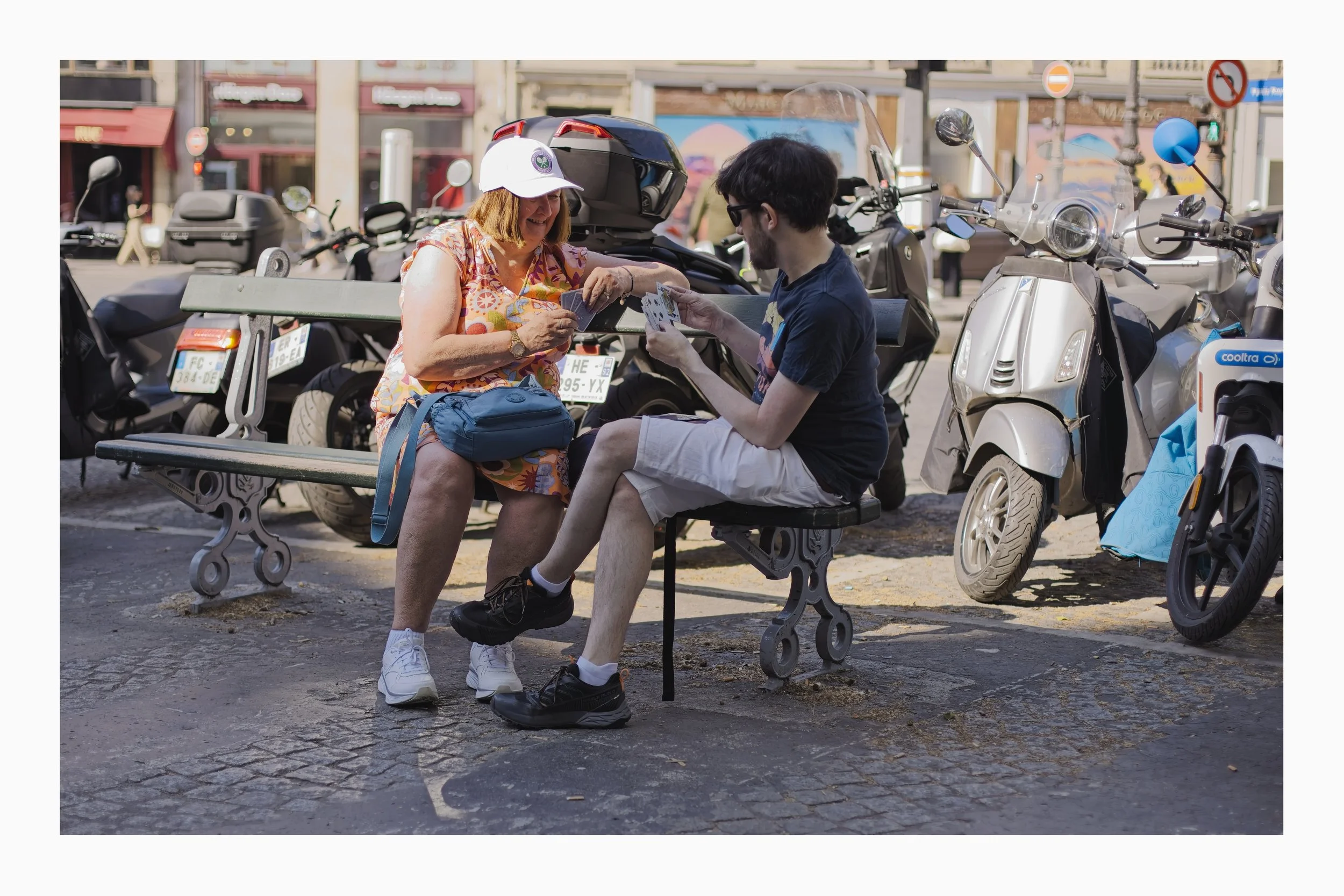 2 people playing cards on a bench in Paris, France