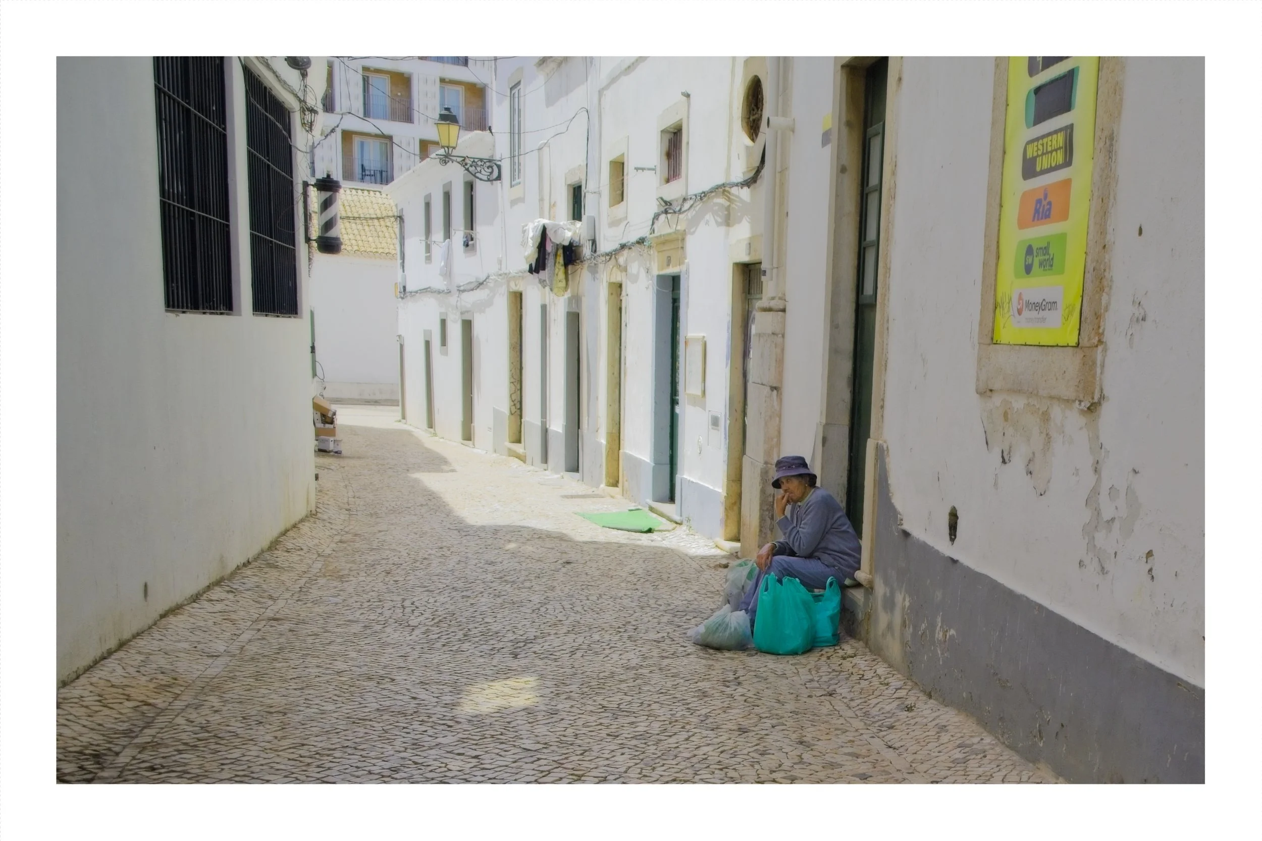 An old woman sitting in a doorway in Faro, Portugal