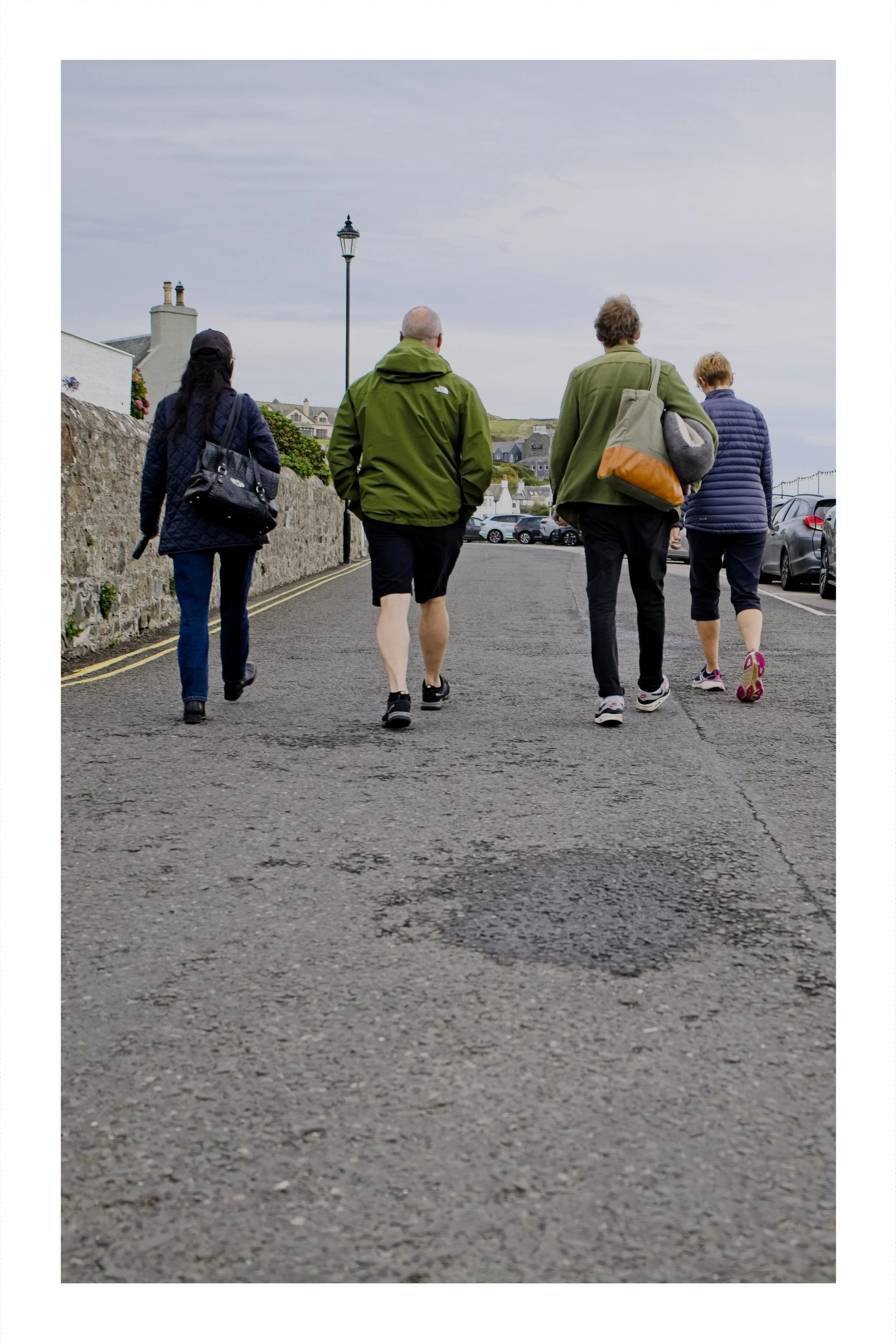 Four people walking along the harbour road in Portpatrick