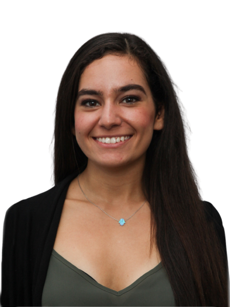 Portrait of a young woman with long dark hair, smiling, wearing a black blazer over a green top with a necklace, against a black background.