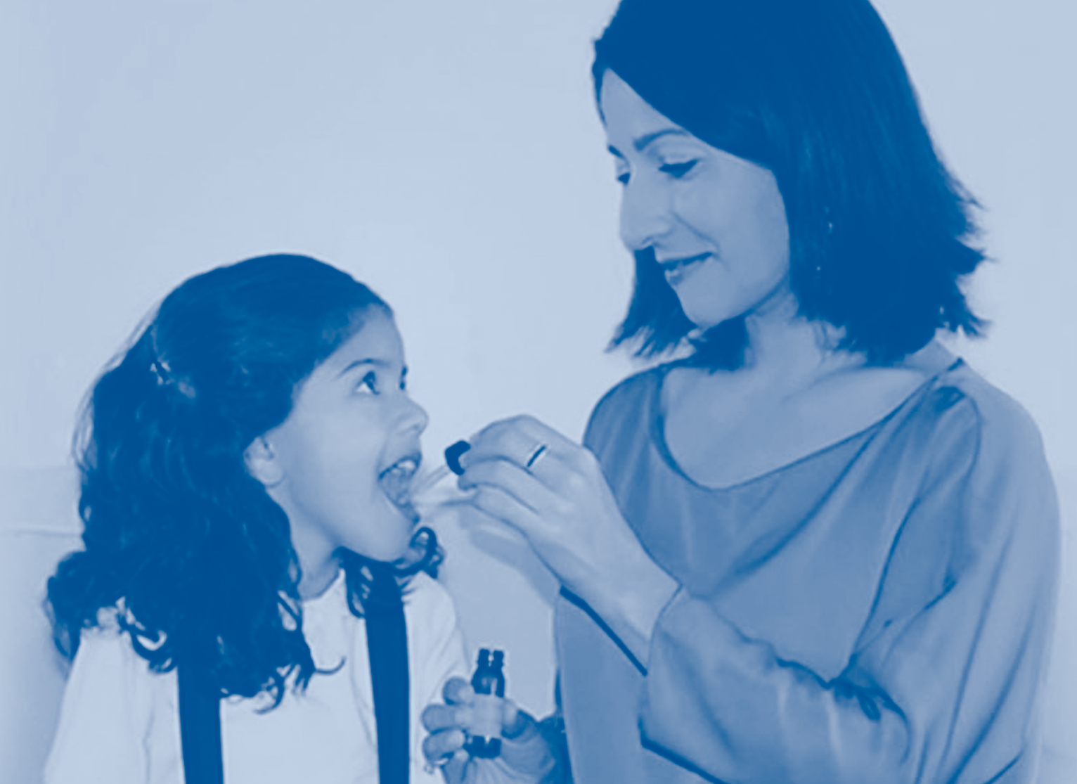 Mother administering sublingual allergy drops to her child.