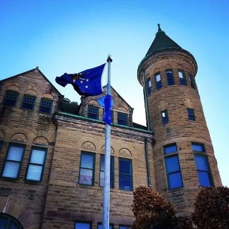old stoney frankfort city hall historic building with indiana flag waving on a sunny blue sky day
