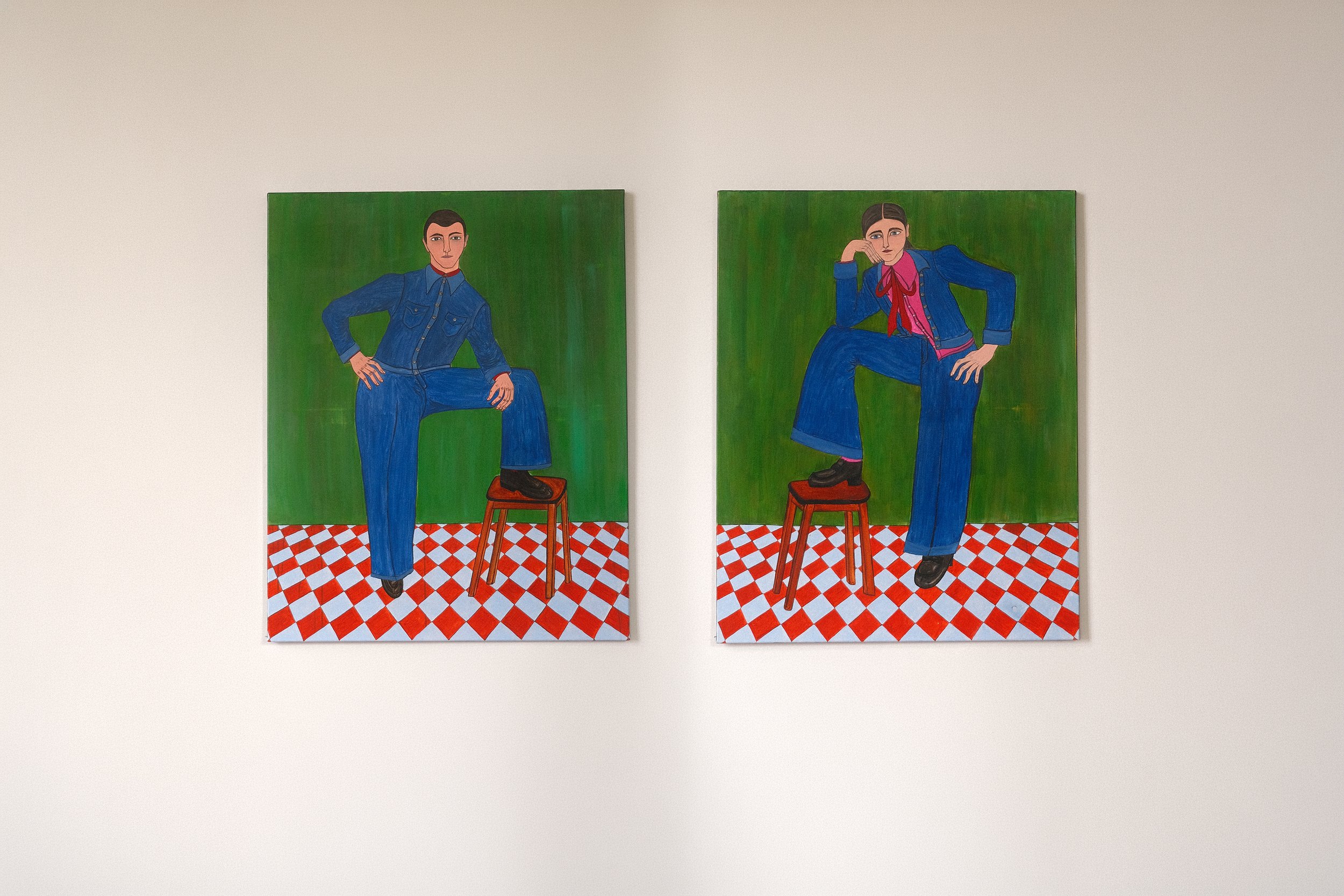 The Guardians. 
2 figurative paintings by Lola Nova of herself in one painting and her husband in the other one. Bold poses, both dressed in denim suits, one foot on a stool and a checkered terracotta-white floor. Vibrant green background. 