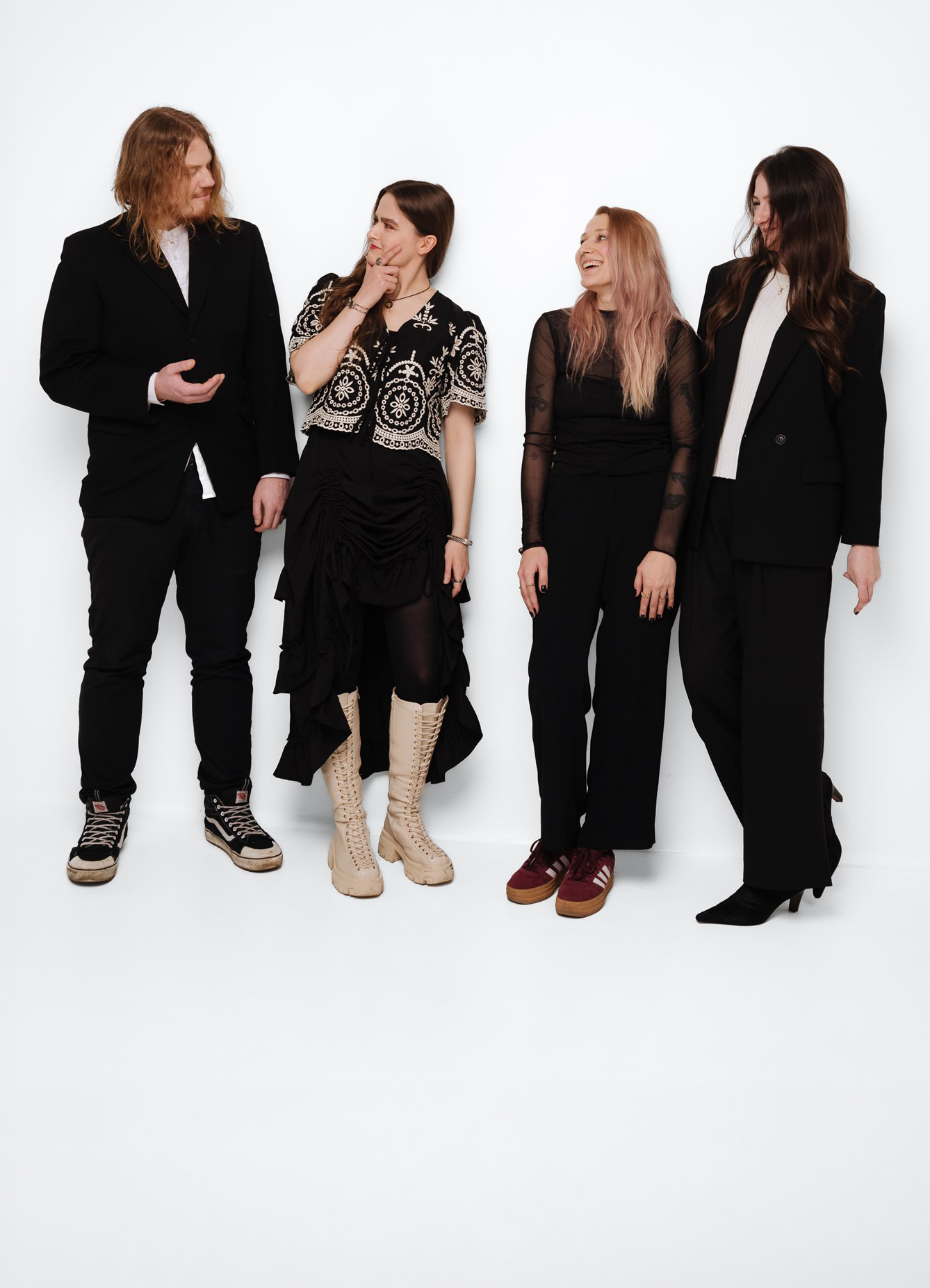 Four people standing against a white background, engaging in conversation and smiling.