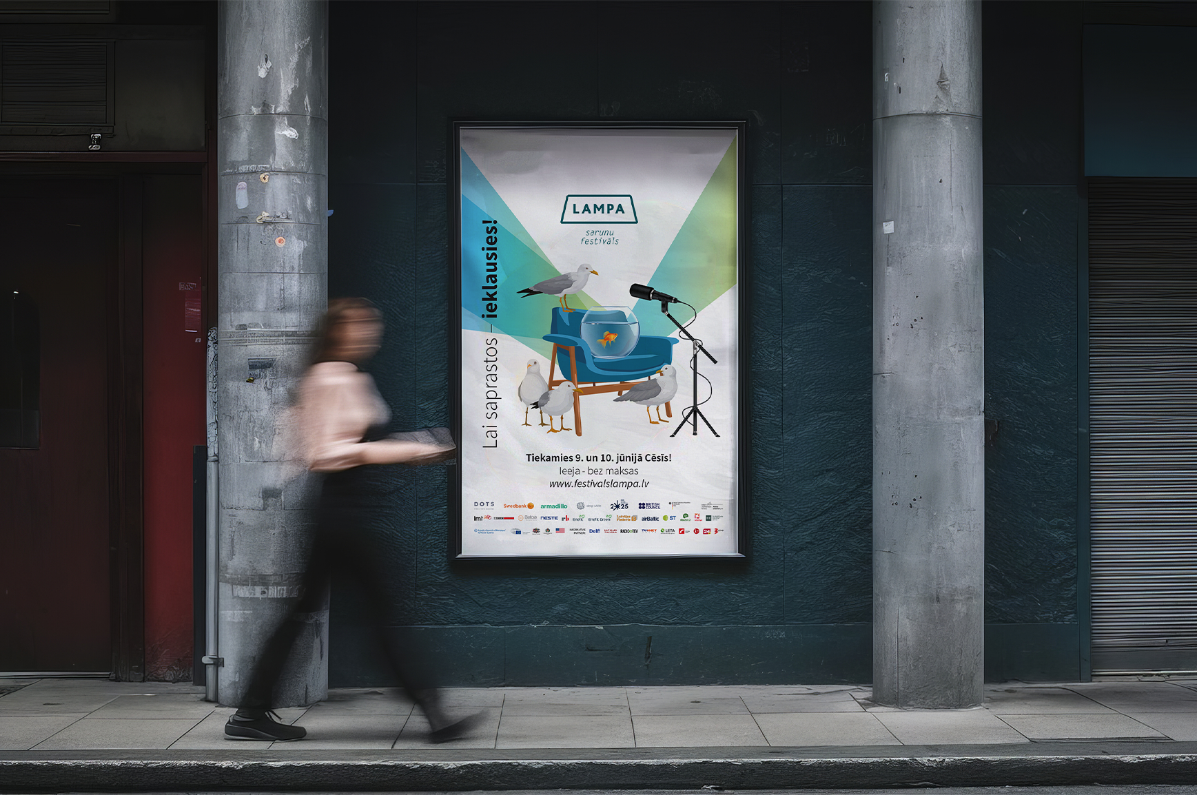 A poster on a dark textured wall promoting a bird watching festival called 'Lampa sarunu festivāls' held on June 9th and 10th, featuring illustrations of seagulls, a fishbowl, and a microphone, with event website and sponsor logos at the bottom. A person with blurred motion is walking past on the sidewalk.