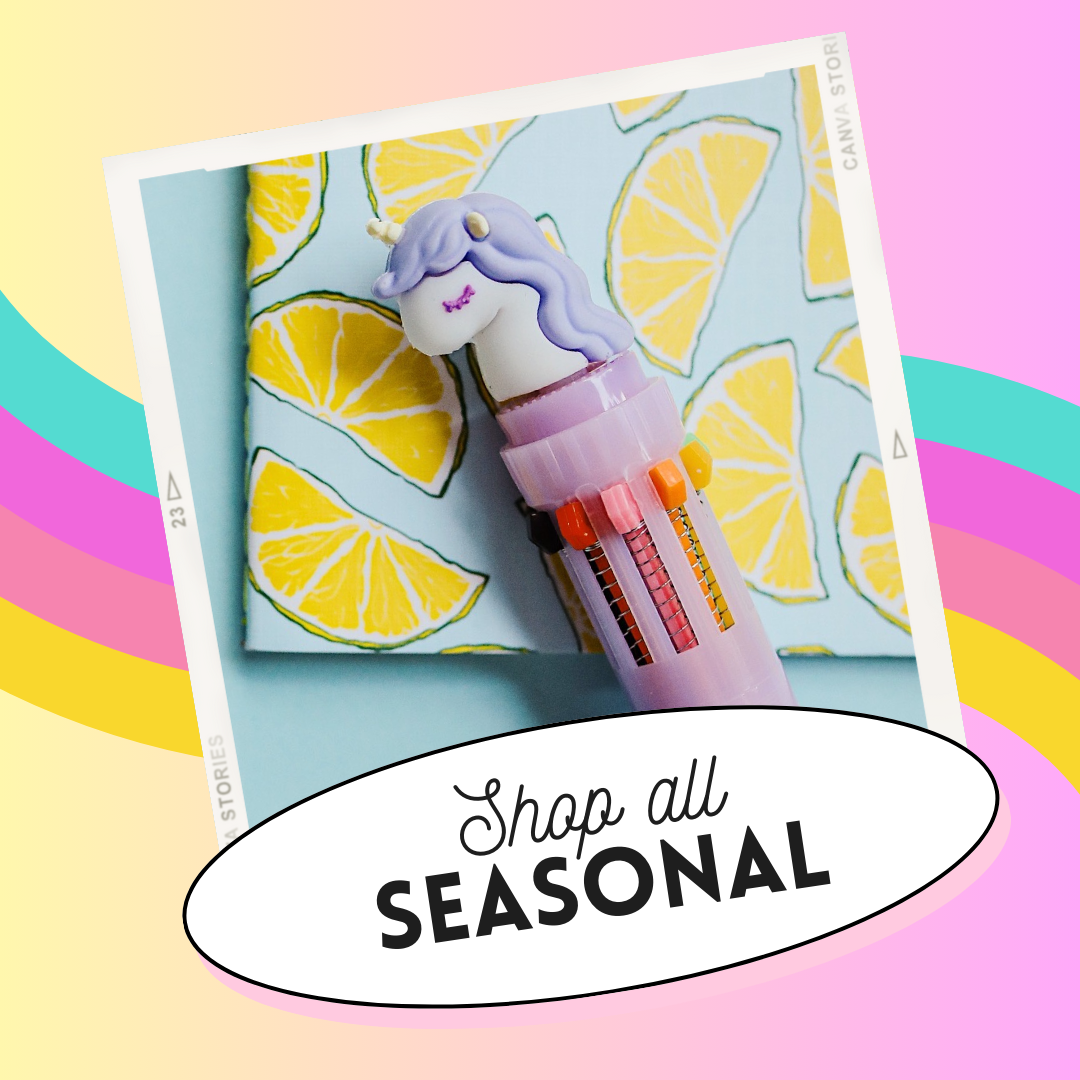 A pastel-colored pen topper with a unicorn design, placed on a blue background with lemon slice illustrations. The image includes a white speech bubble with the text "Shop all SEASONAL".