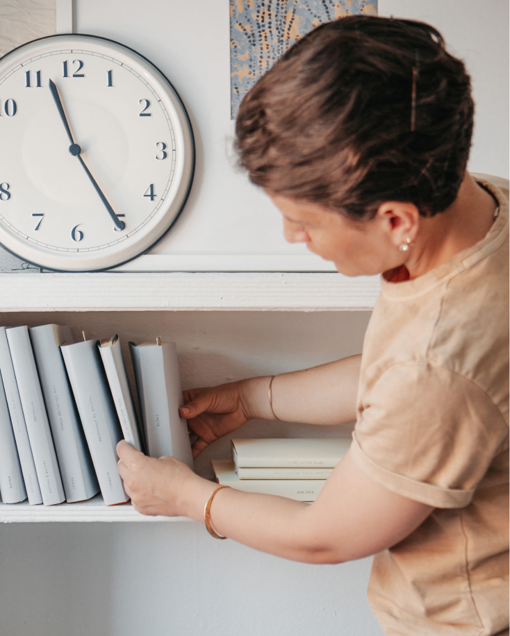 A woman organizing custom books on a bookshelf.