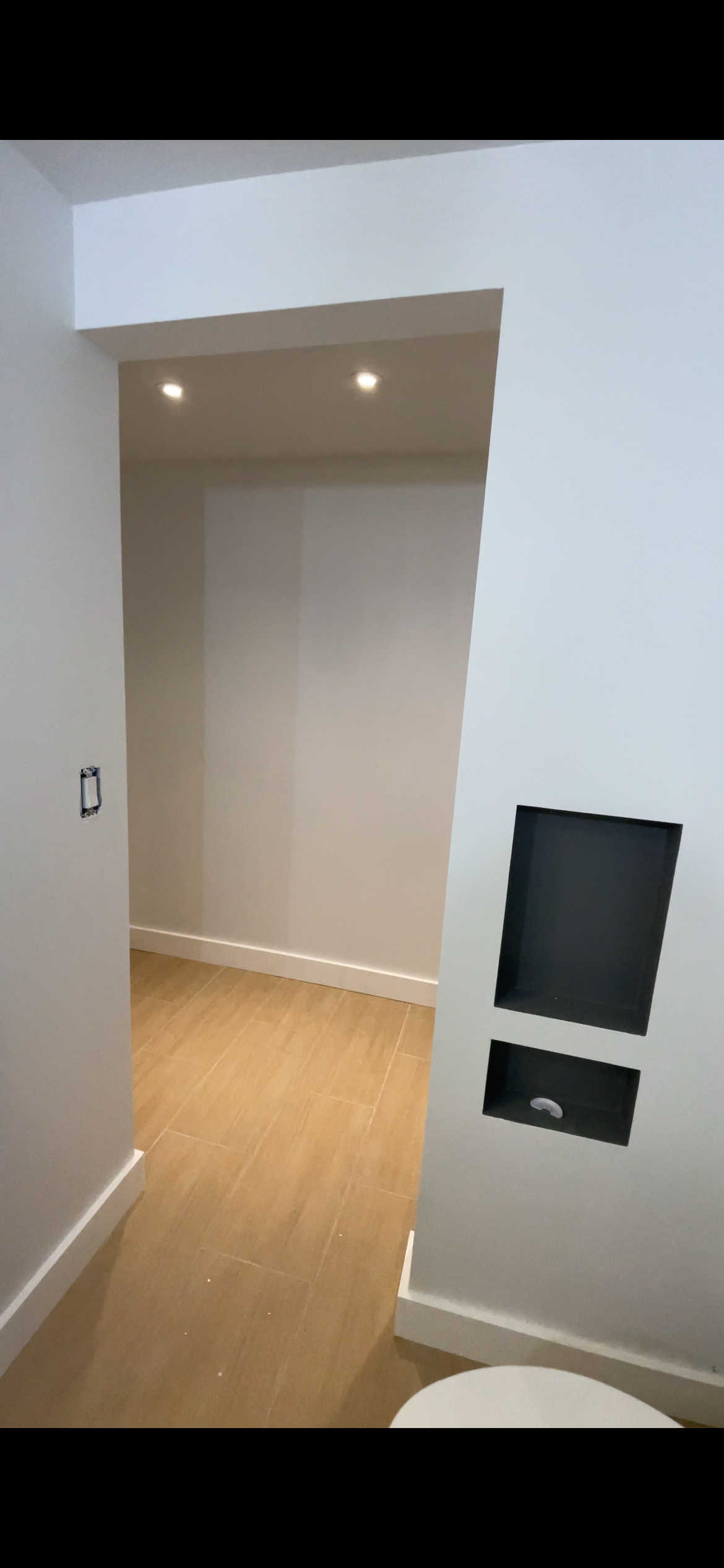 Partially finished room with unfinished wall, recessed lighting, and a small hidden storage or access panel.