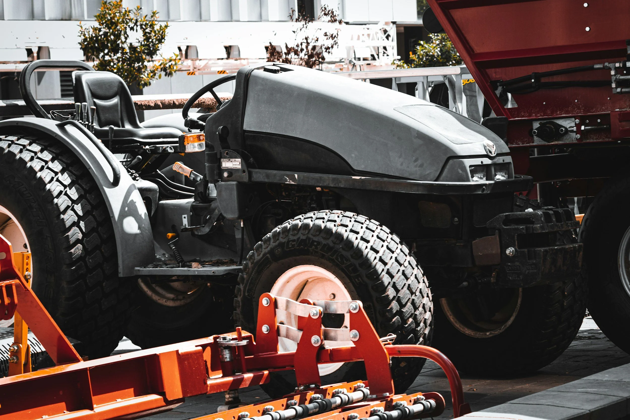 Close-up of a grey tractor with large tires parked outdoors.