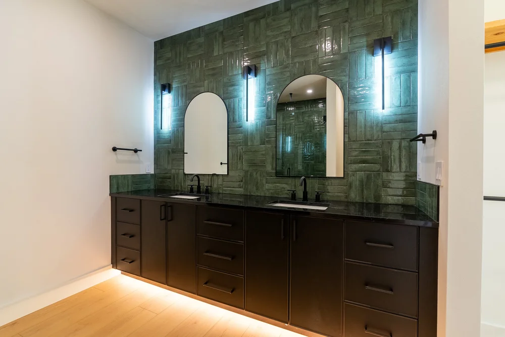 Dark double vanity against green bathroom tile