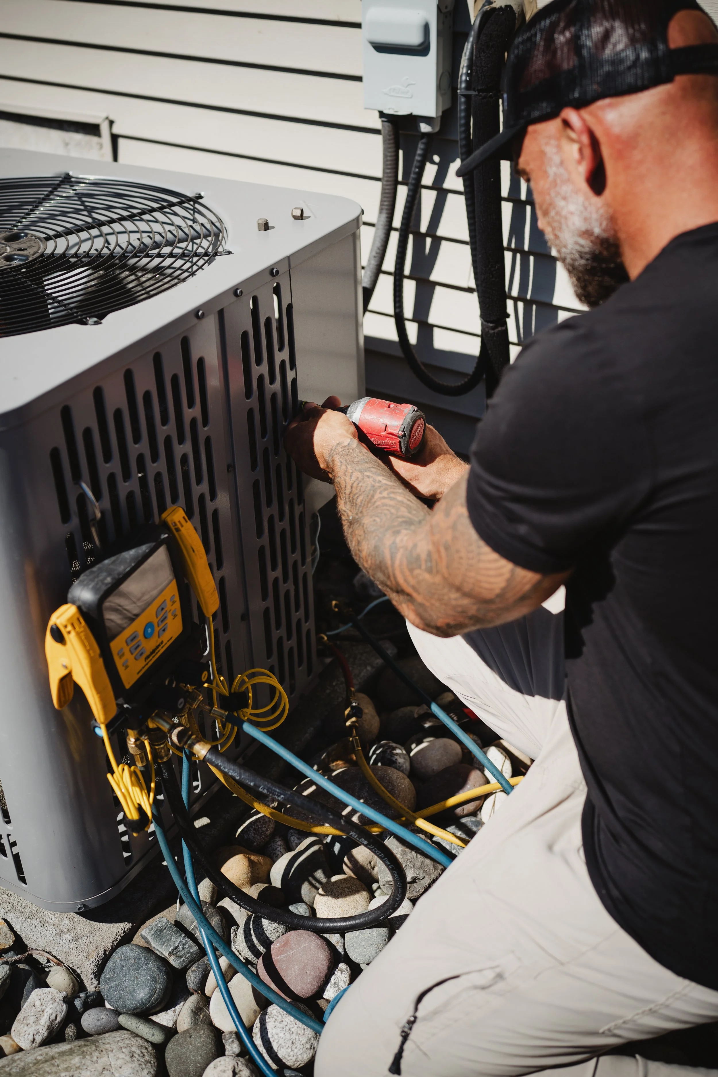 Technician working on an outdoor HVAC unit with tools connected to the system.