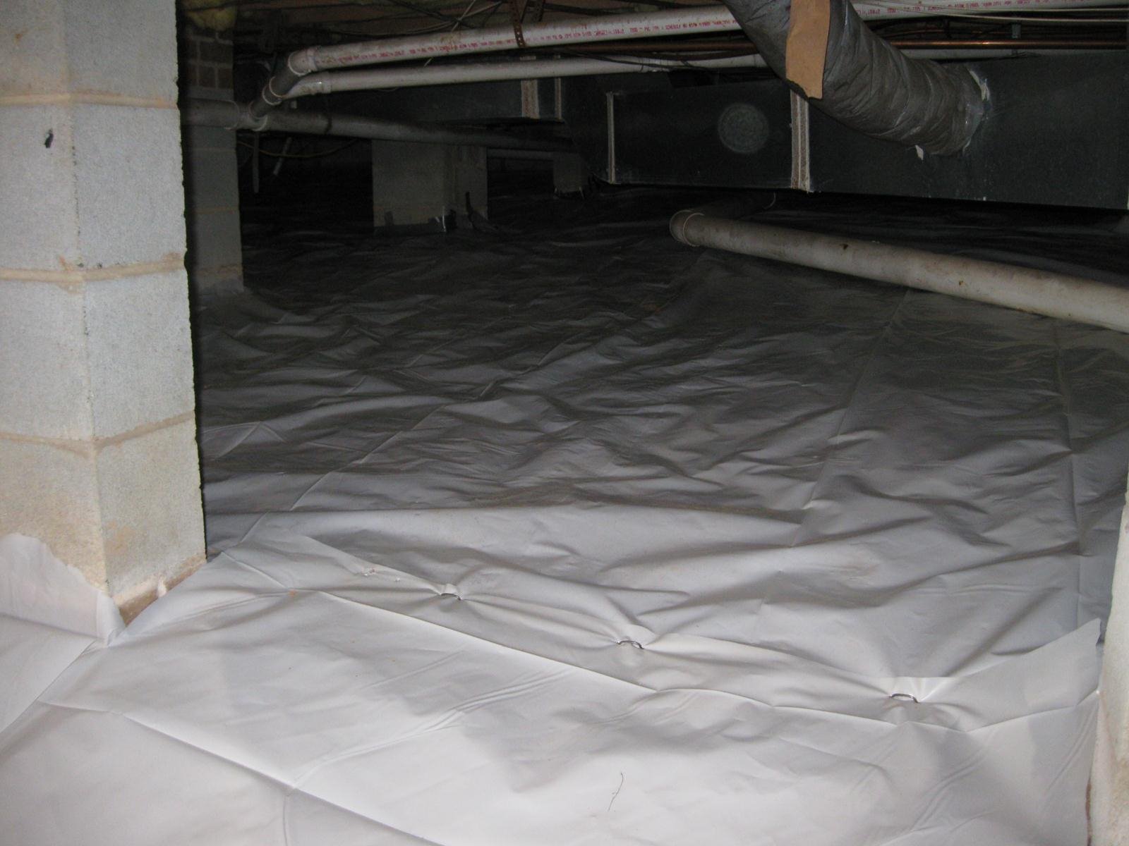 Construction or renovation area with waterproof plastic sheeting spread on the floor and covering pipes and surfaces.