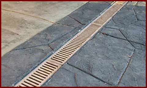 Close-up of a floor drain in a tiled concrete surface.