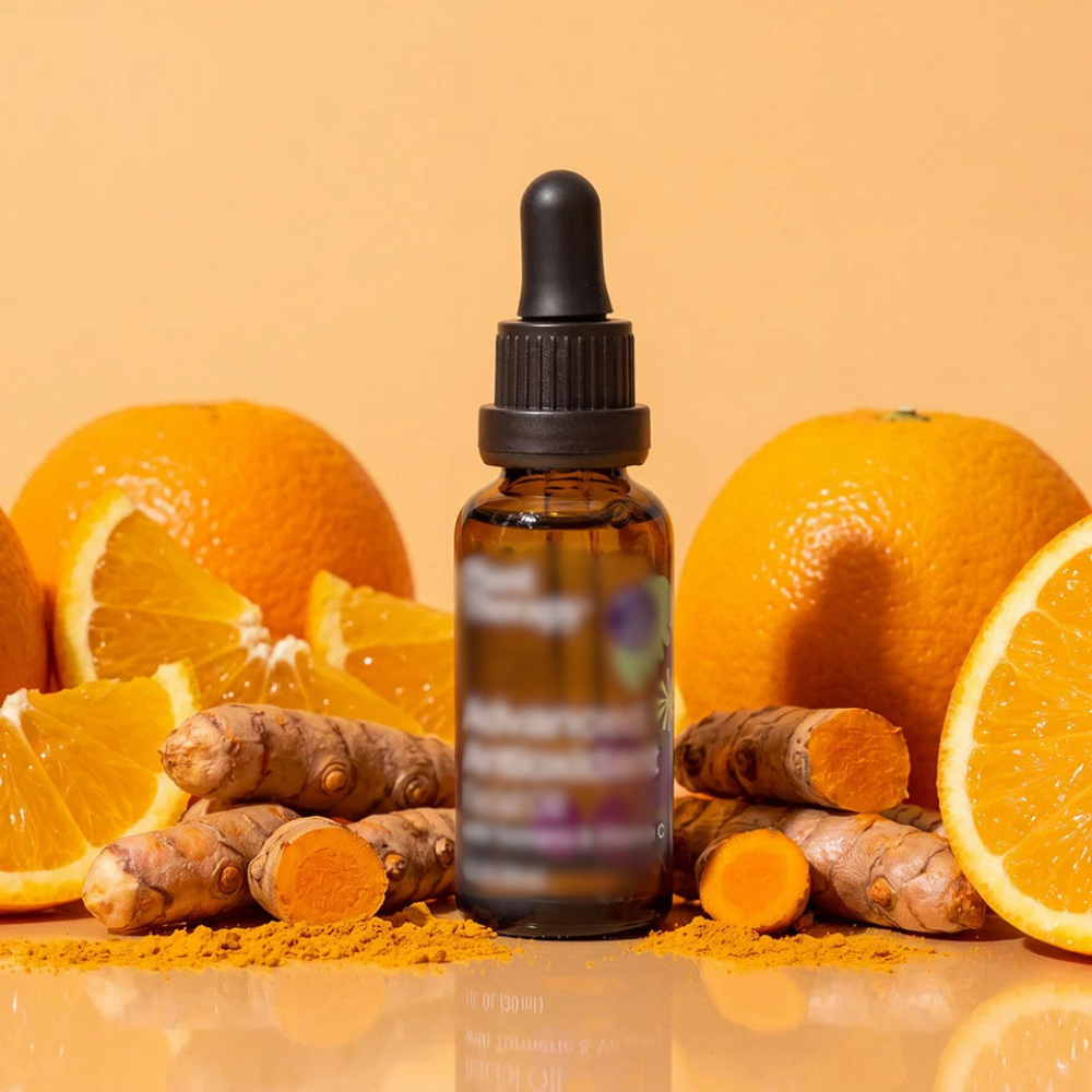 A small glass bottle with a dropper cap surrounded by fresh oranges, orange slices, turmeric roots, and turmeric powder, all on a reflective surface.