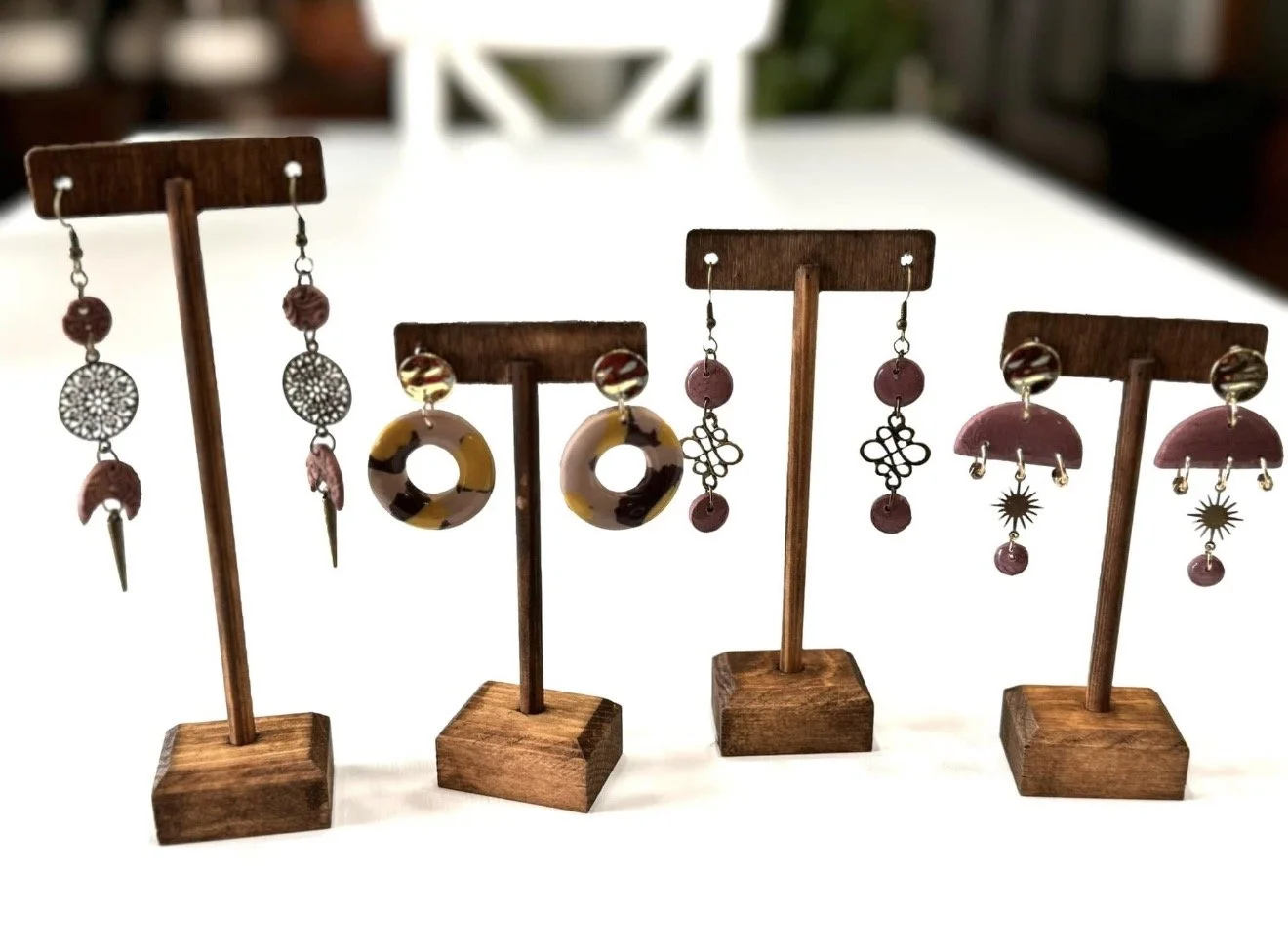 four pairs of earrings on display on a white table
