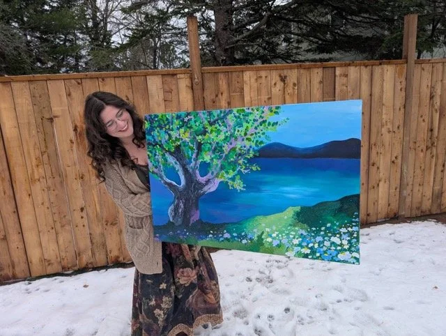 Artist Jenna holding up a large landscape painting