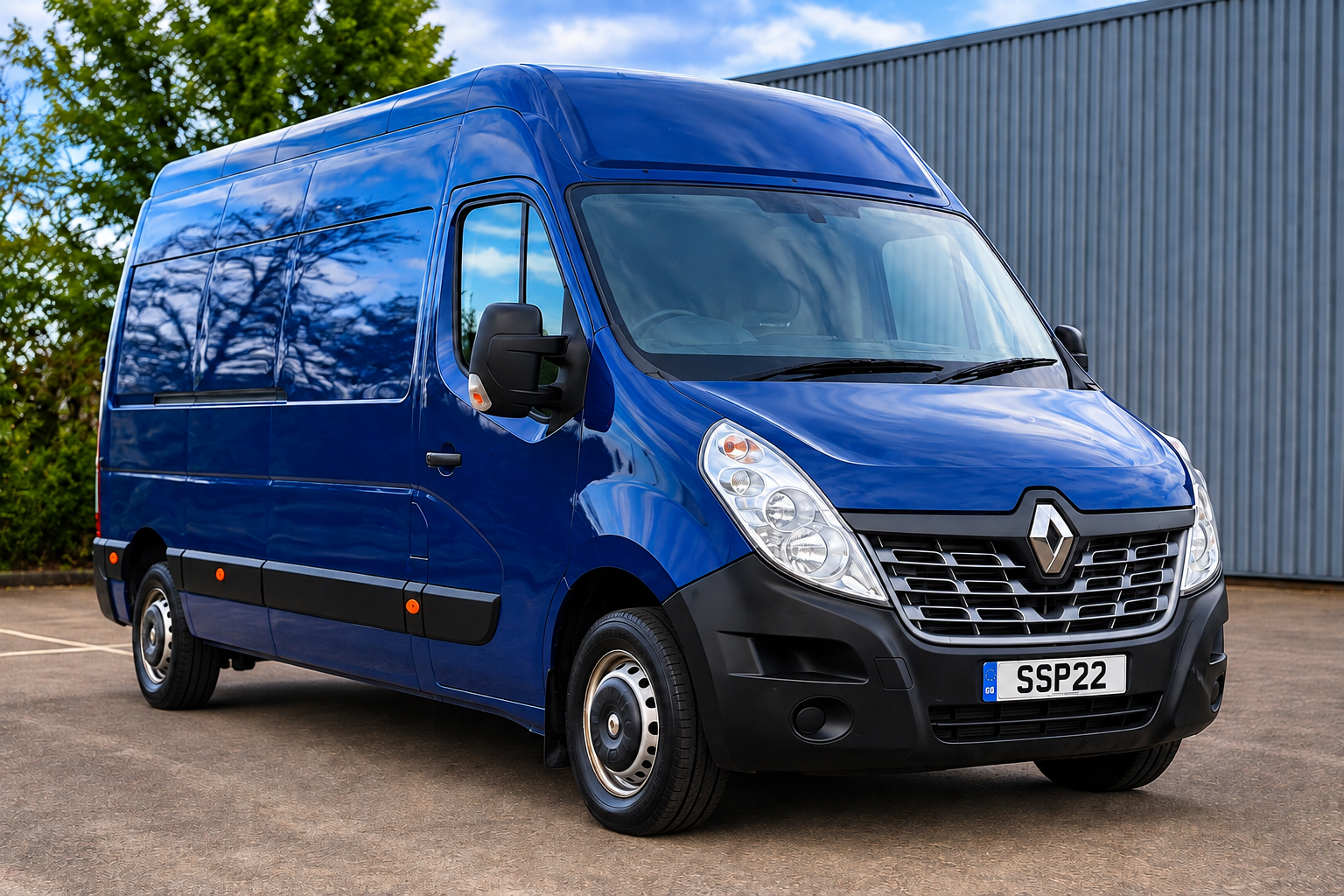 Blue Renault commercial cargo van parked outdoors near a building and trees.