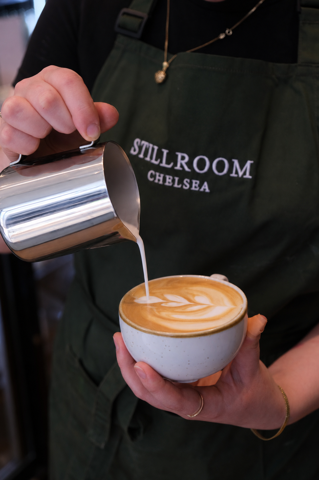 Barista pouring latte art at Stillroom Chelsea.