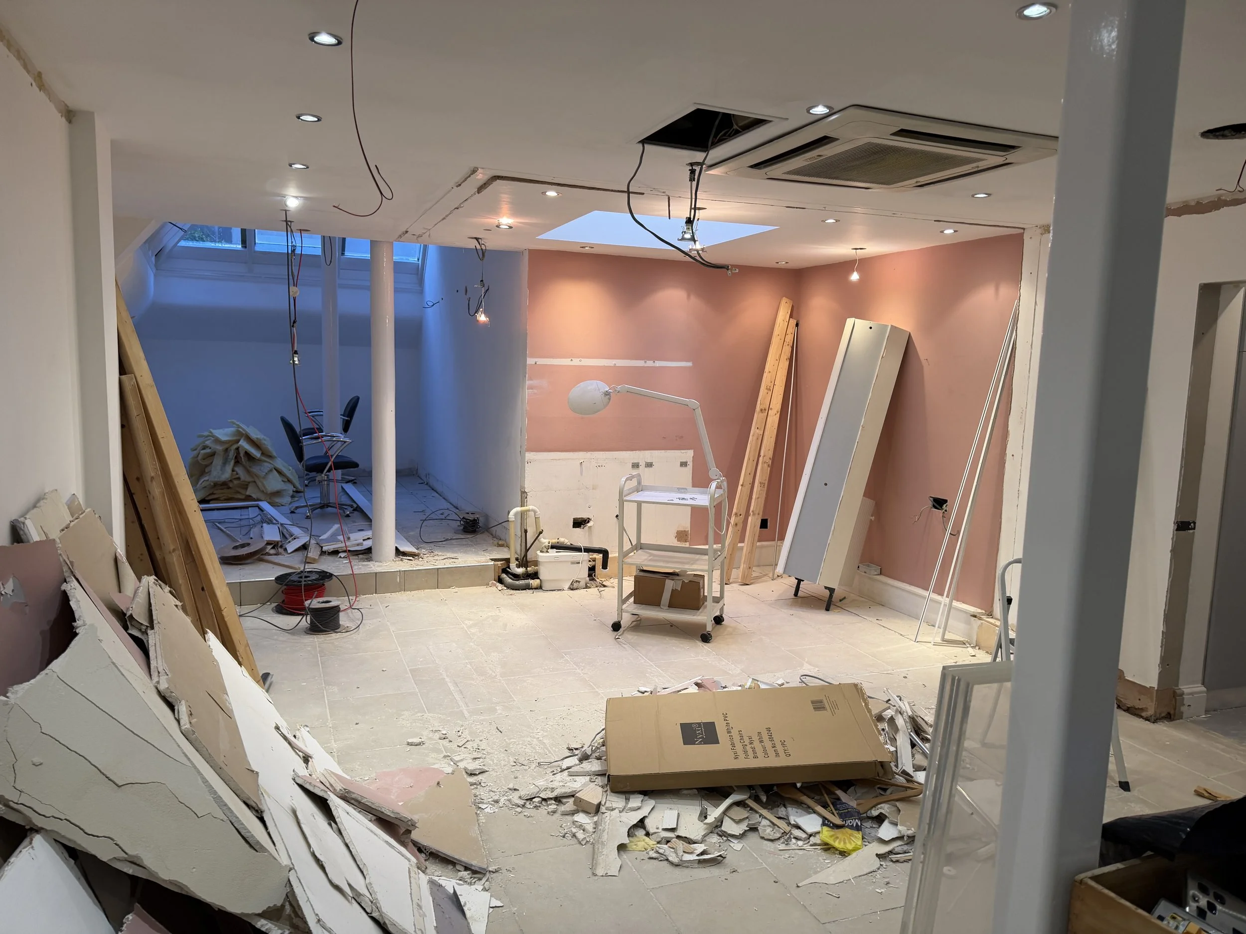 Interior of a room under renovation with debris, tools, and unfinished ceiling.