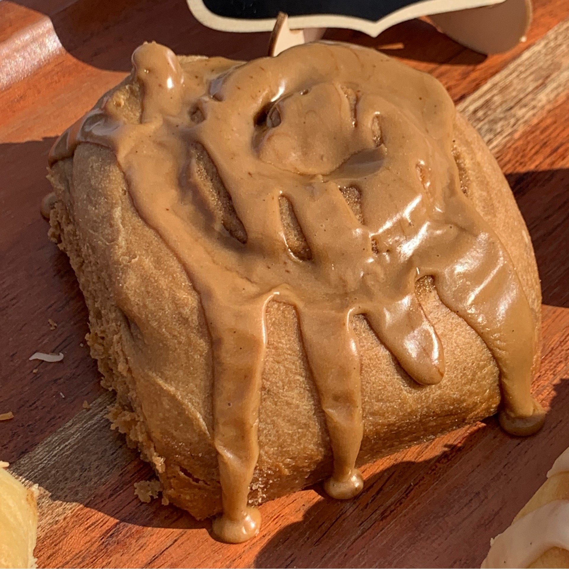 A Scroll topped with warm caramel sauce on a wooden cutting board