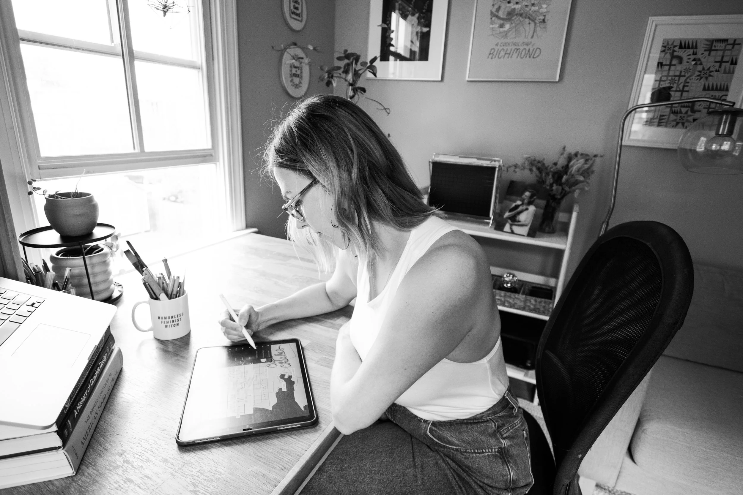 A portrait of illustrator Laura Sant in her studio, drawing on a tablet.