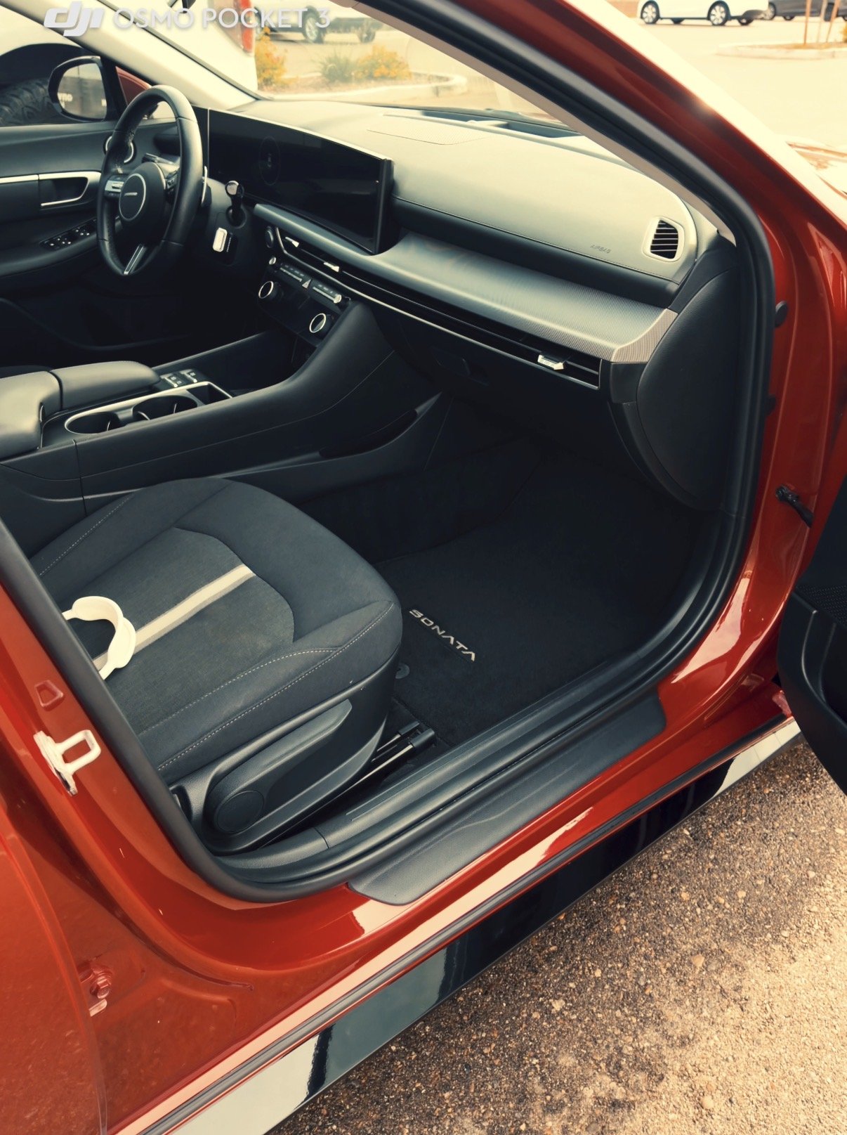 The interior of a red Toyota Sora vehicle showing the driver's seat, dashboard, steering wheel, and center console with cup holders.