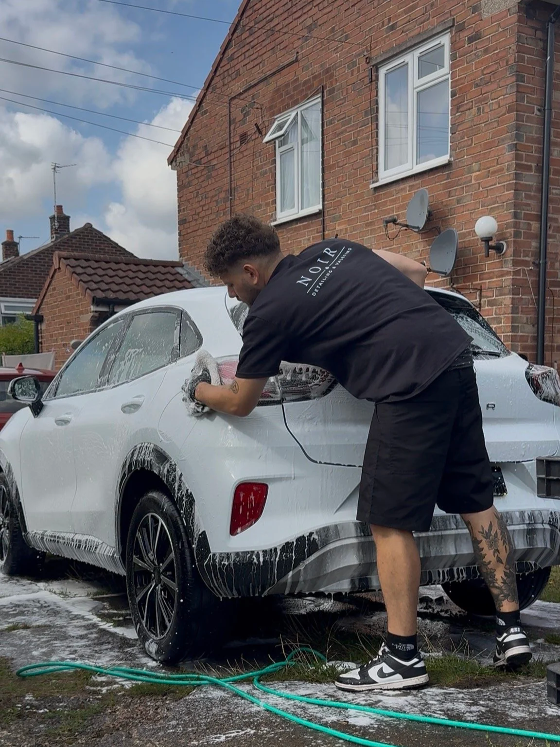Luke from Noir Detailing & Valeting hand washing a car during a mobile valet in Cheshire
