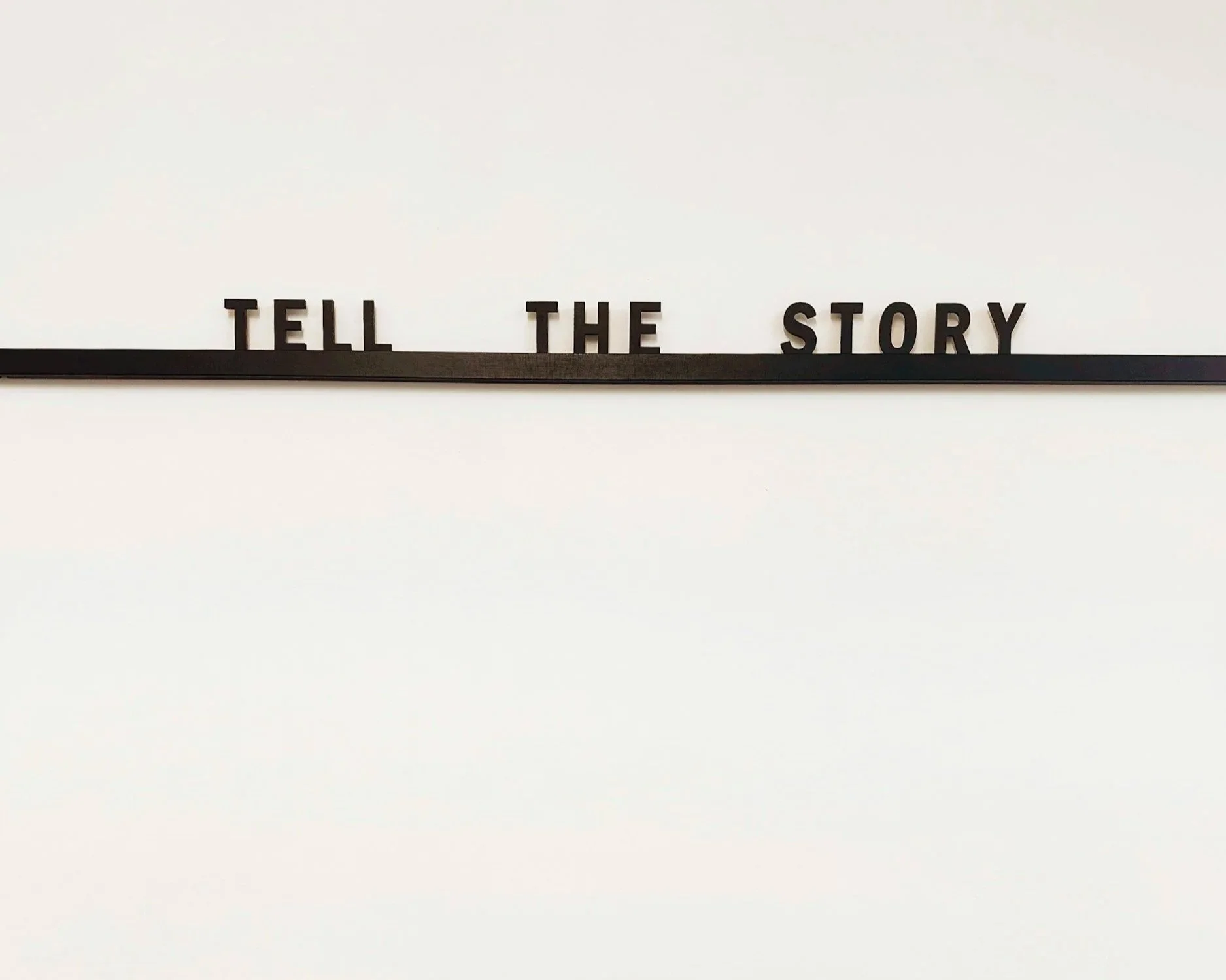 A whiteboard with black letters spelling 'TELL THE STORY' on a black strip at the bottom.