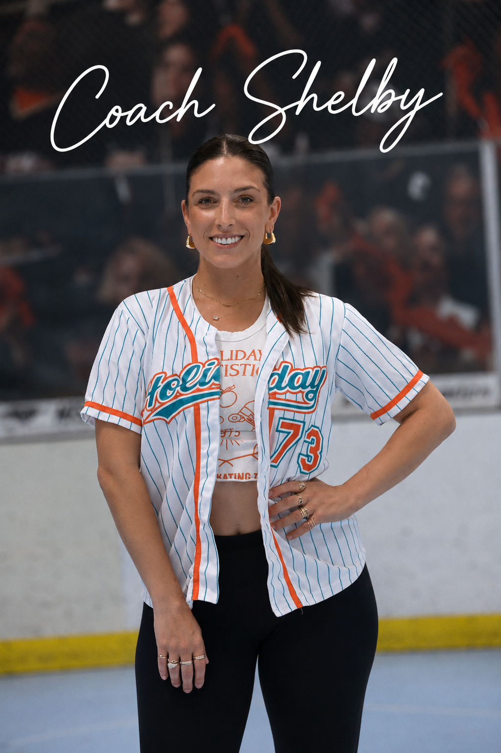 A woman smiling at the camera, wearing a baseball-style jersey with the number 73, standing in front of a blurred crowd and a banner that reads 'Coach Shelby'.